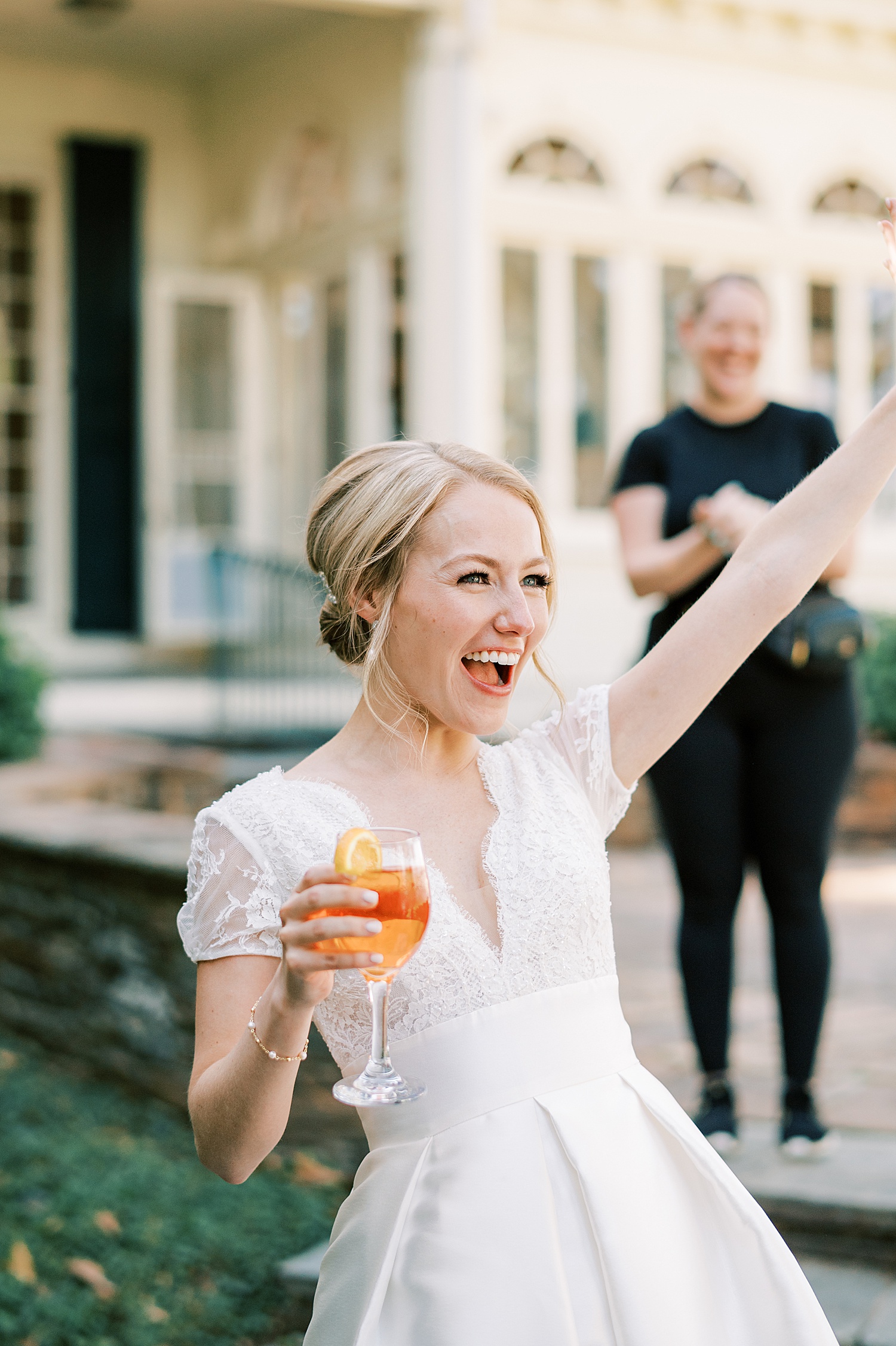 bride holds glass of wine and cheers 