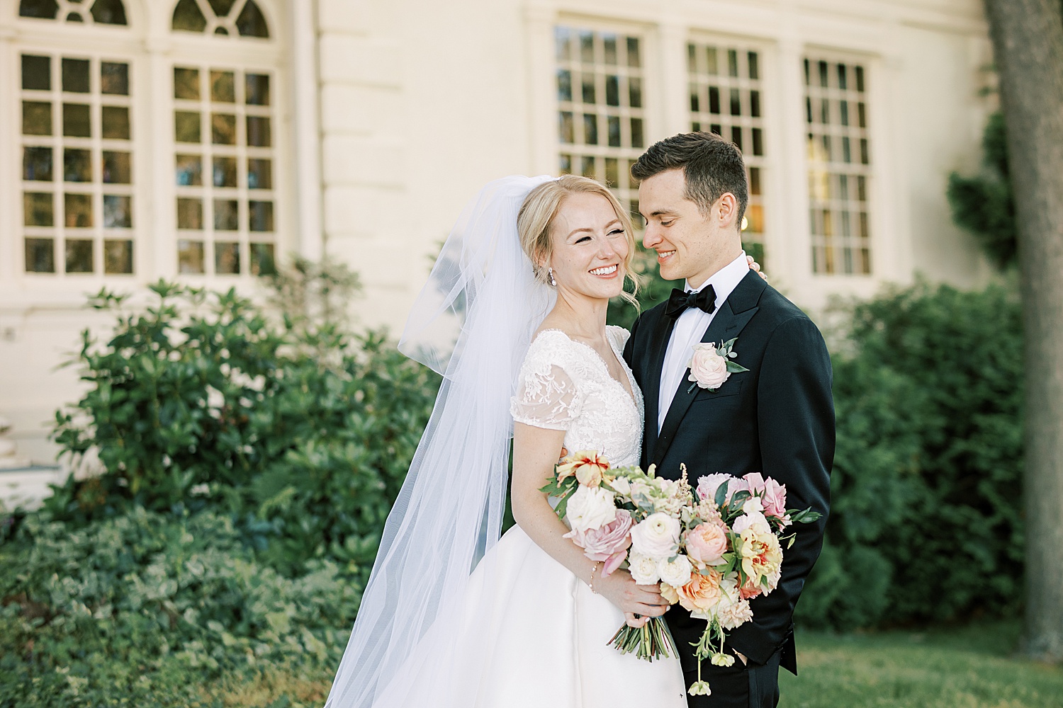 groom smiles at bride with veil and summer bouquet 