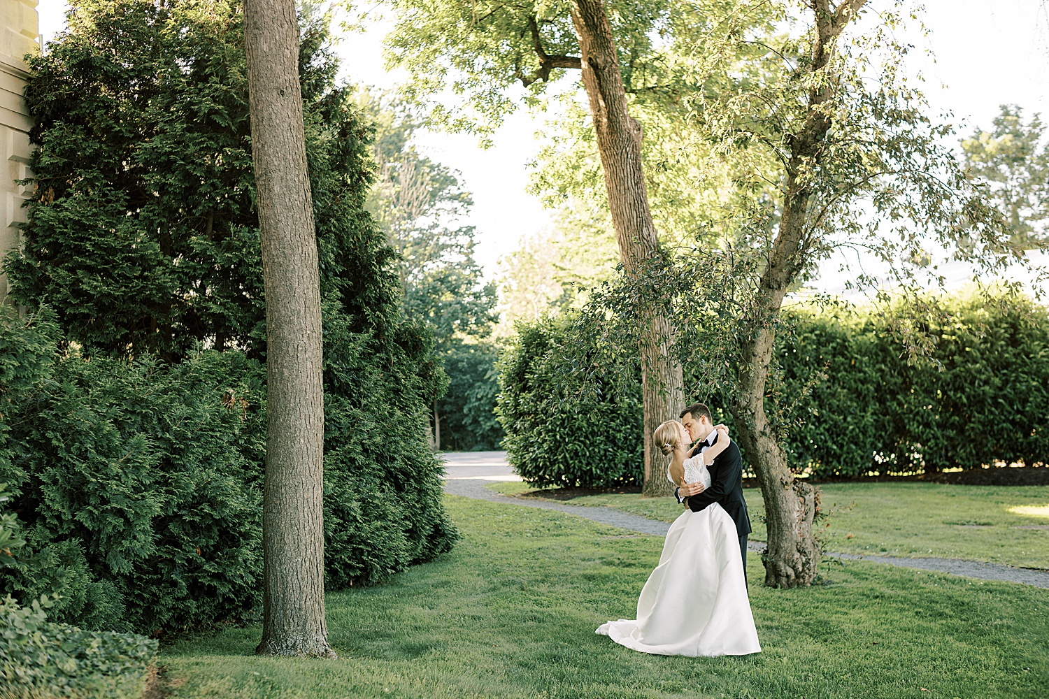 bride and groom kiss on lawn at Glen Foerd on the Delaware