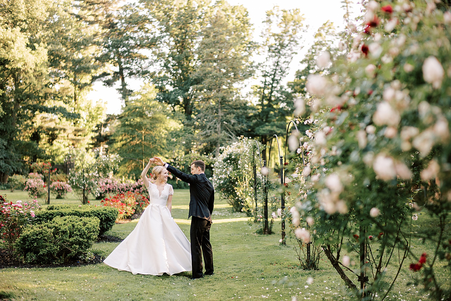 groom twirls bride in rose garden at Glen Foerd on the Delaware
