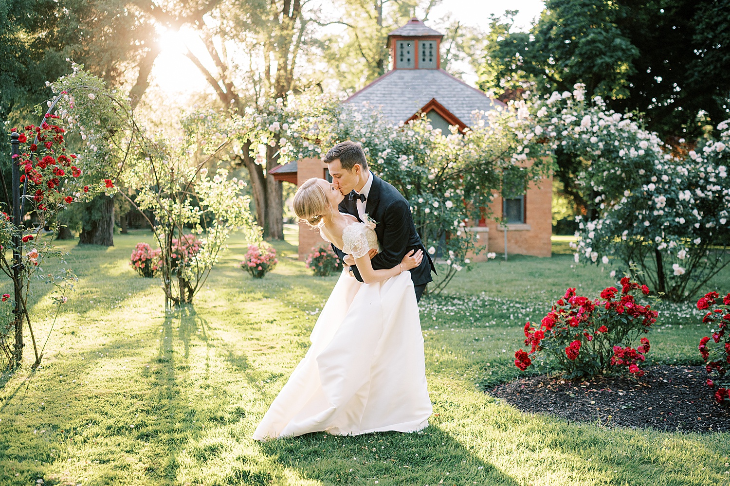 groom dips bride kissing her in rose garden at Glen Foerd on the Delaware