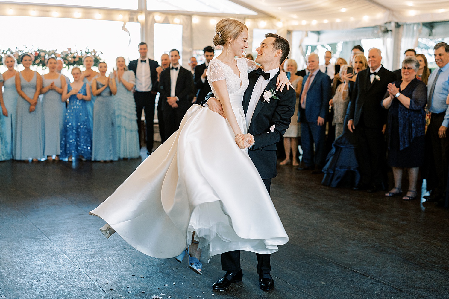 groom lifts bride twirling her during first dance 