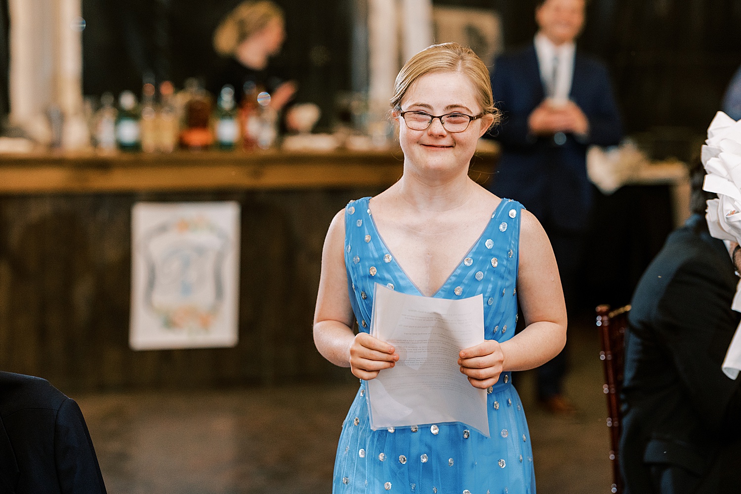 woman with Down syndrome holds paper to read during reception 