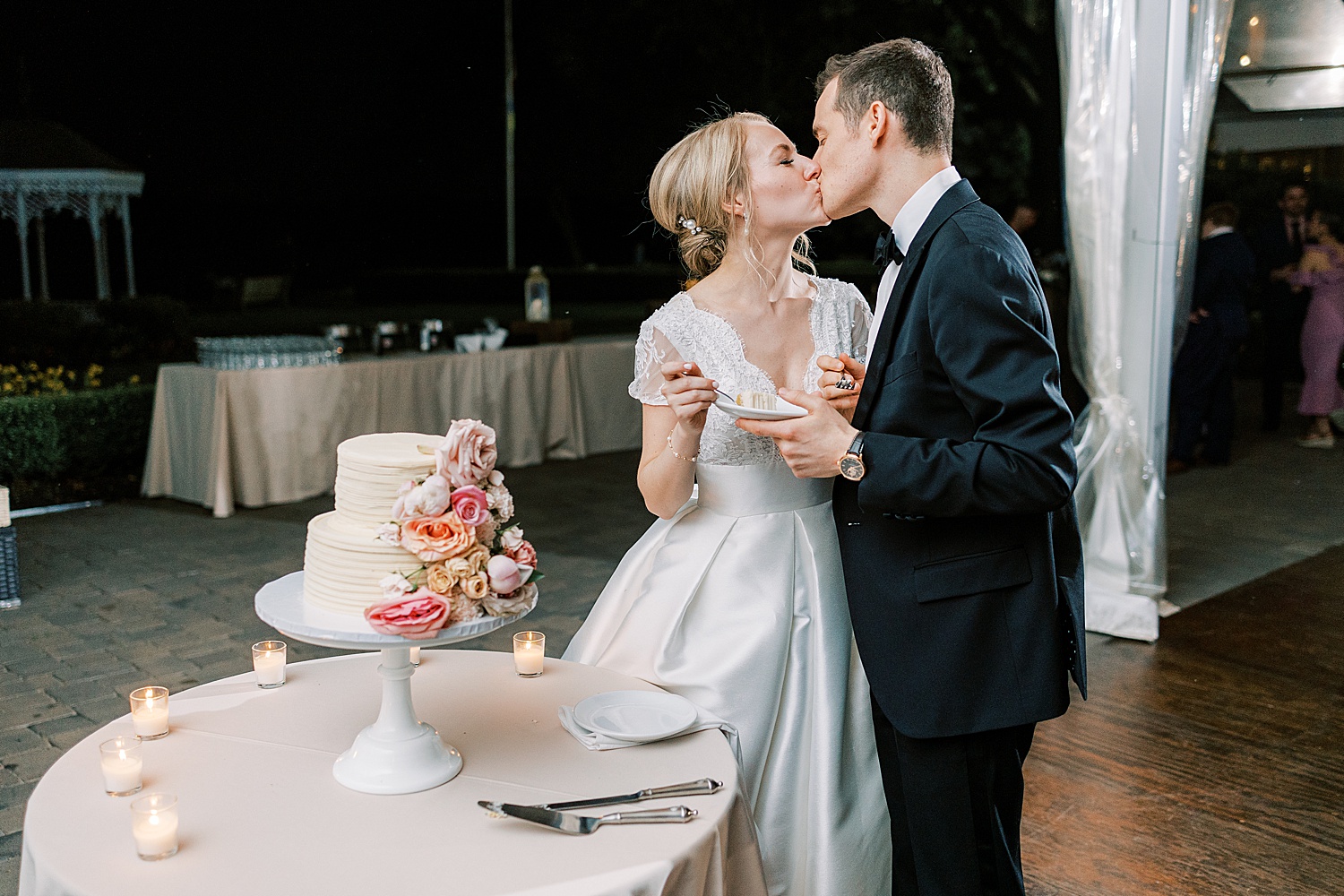 newlyweds kiss after cutting cake during Philadelphia PA wedding reception