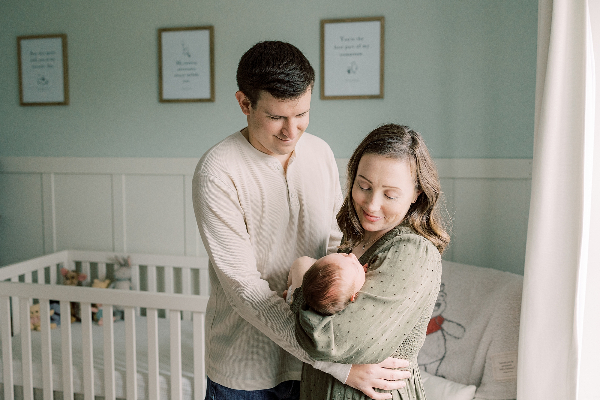 new parents hold son by window during Media PA newborn session