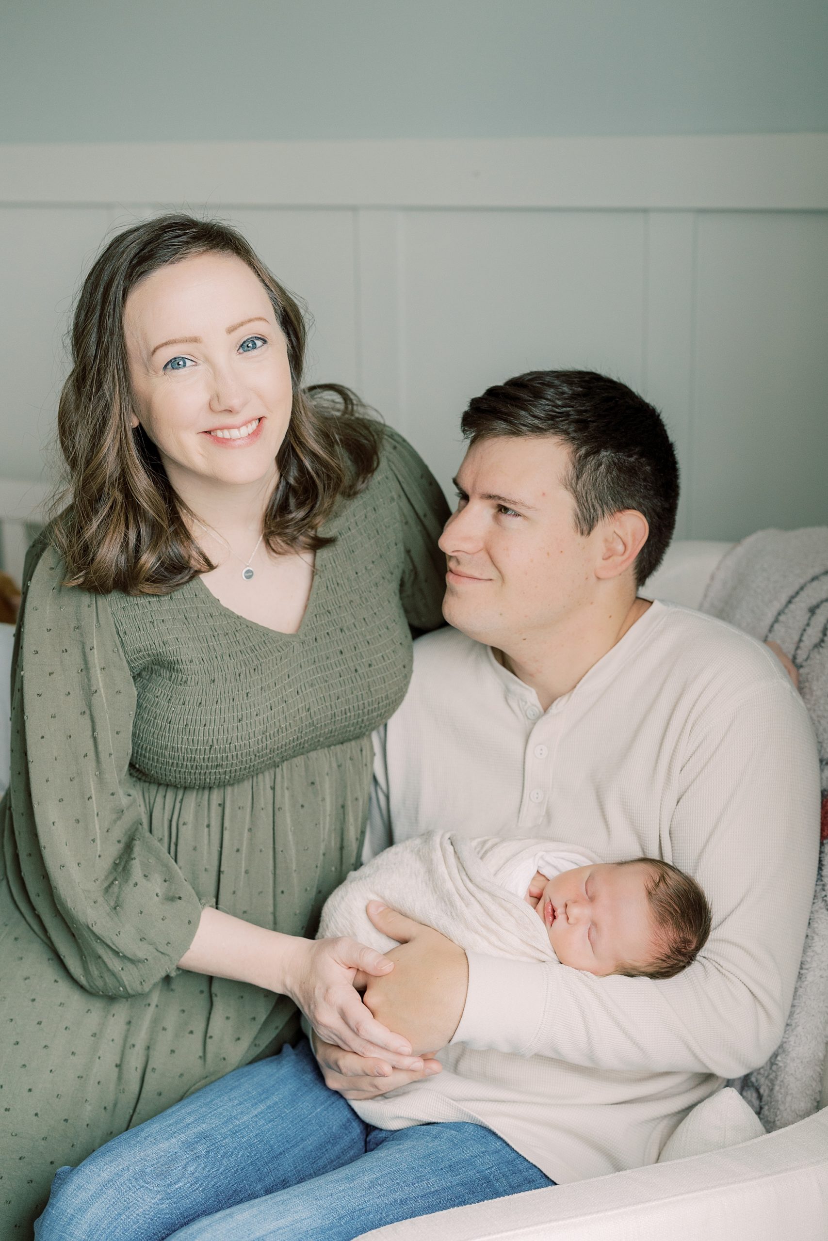 parents smile holding baby in rocker during lifestyle newborn photos 