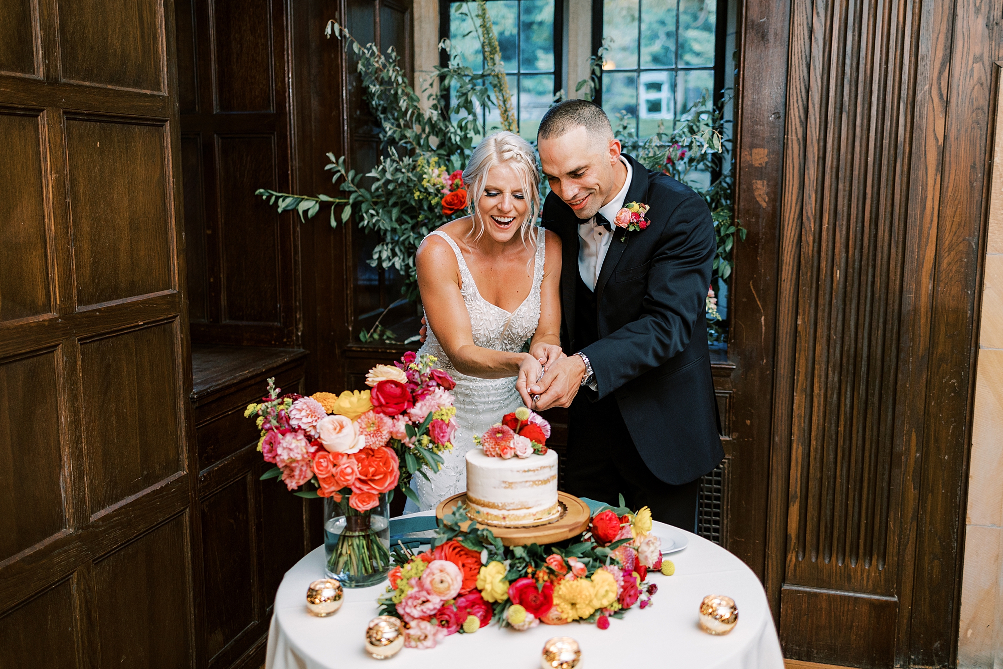 newlyweds cut wedding cake with bright flowers on cake 