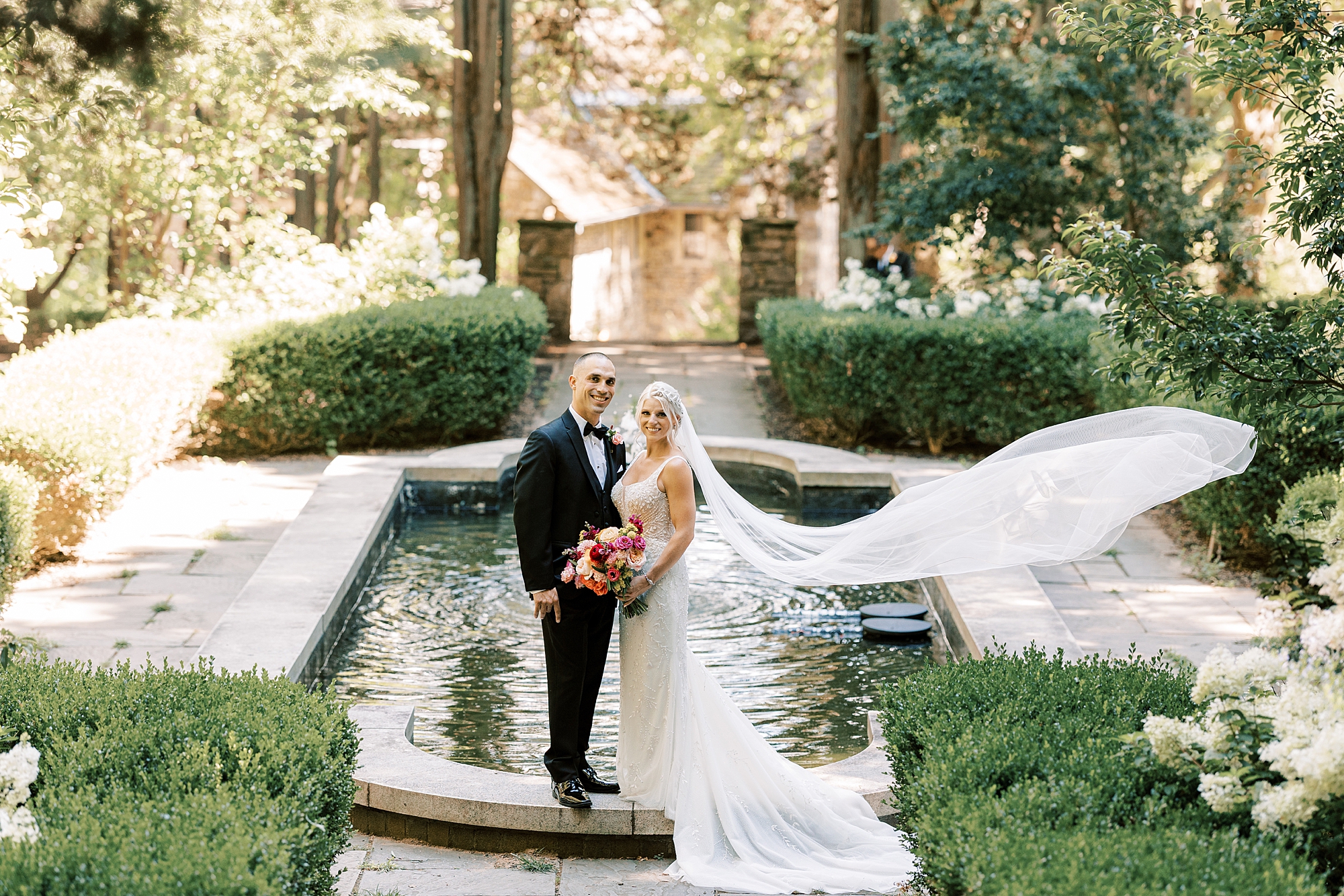 newlyweds stand on edge of pond at Parque Ridley Creek