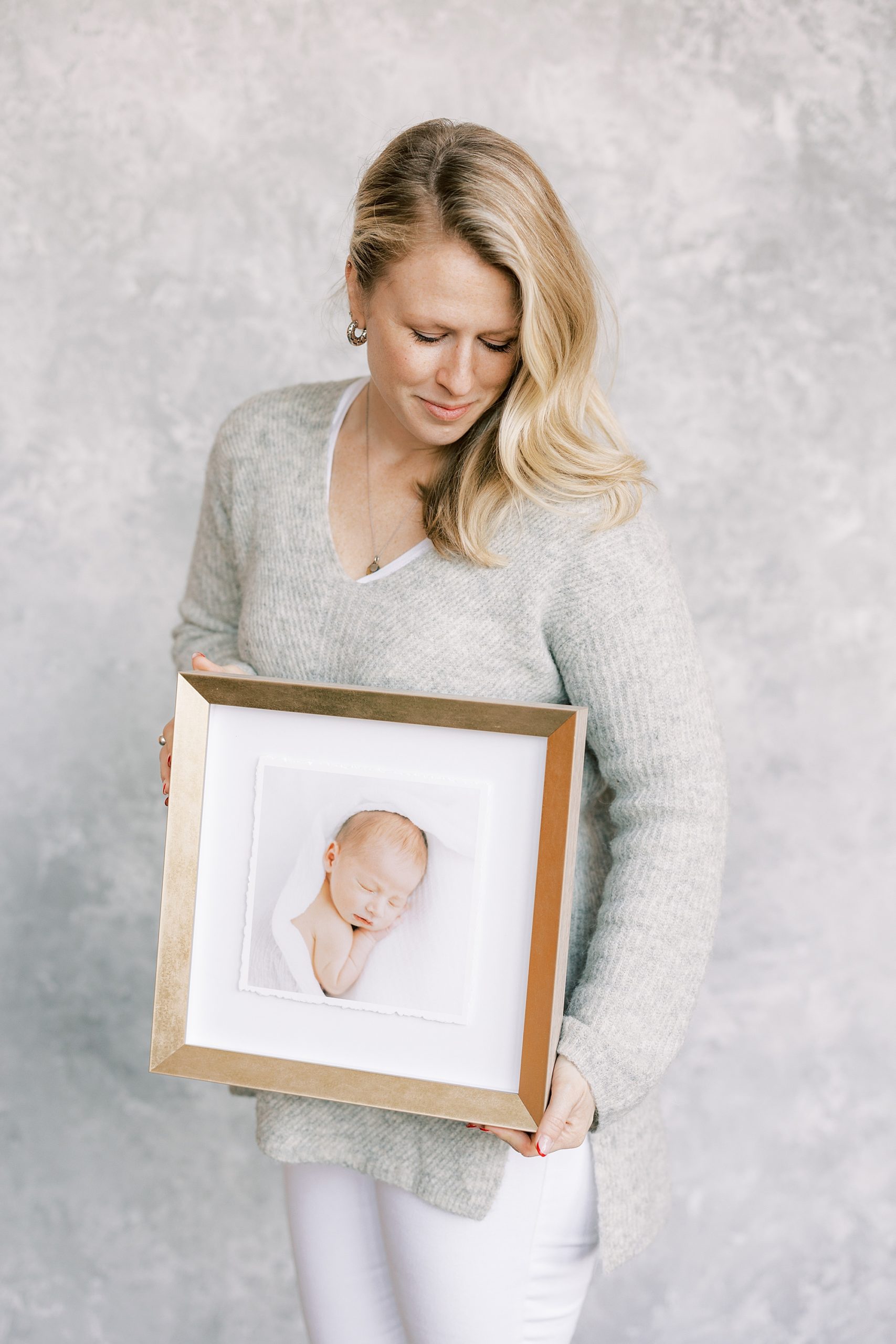 Philadelphia PA newborn photographer holds 16x16 matted photograph of newborn session 