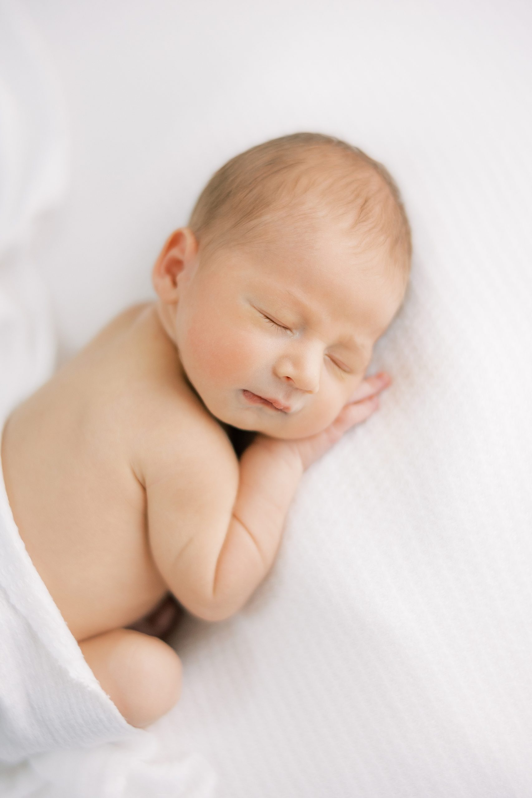 baby lays on white blanket during Philadelphia lifestyle newborn session 