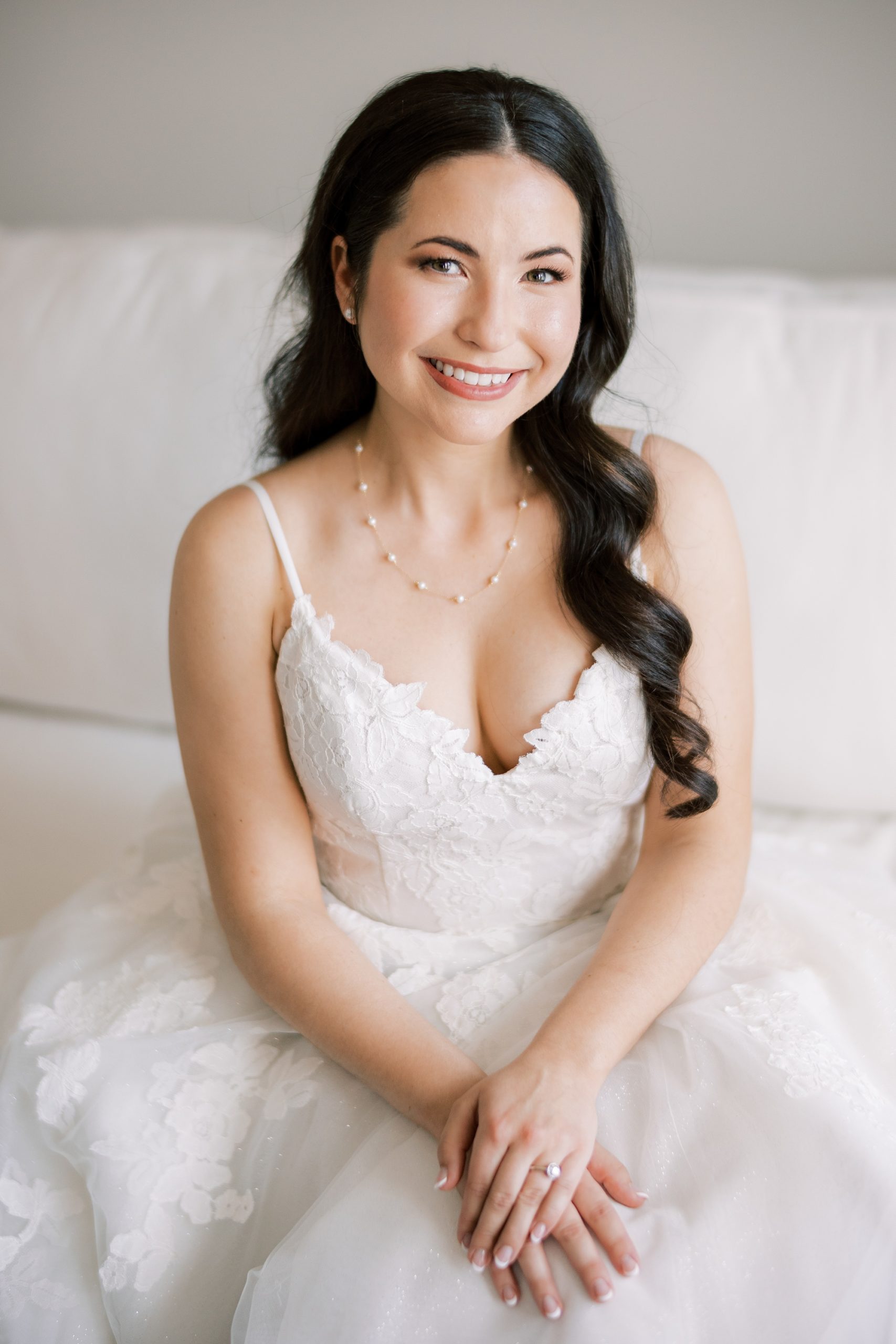 bride smiles sitting in wedding dress on couch 