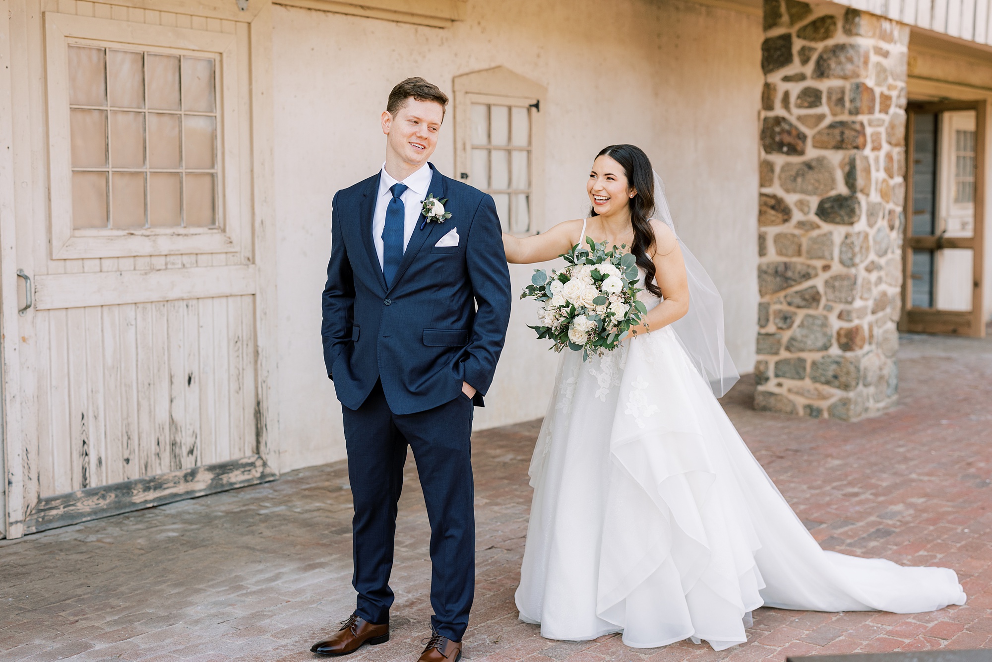 bride reaches for groom's shoulder during first look outside French Creek Golf Club