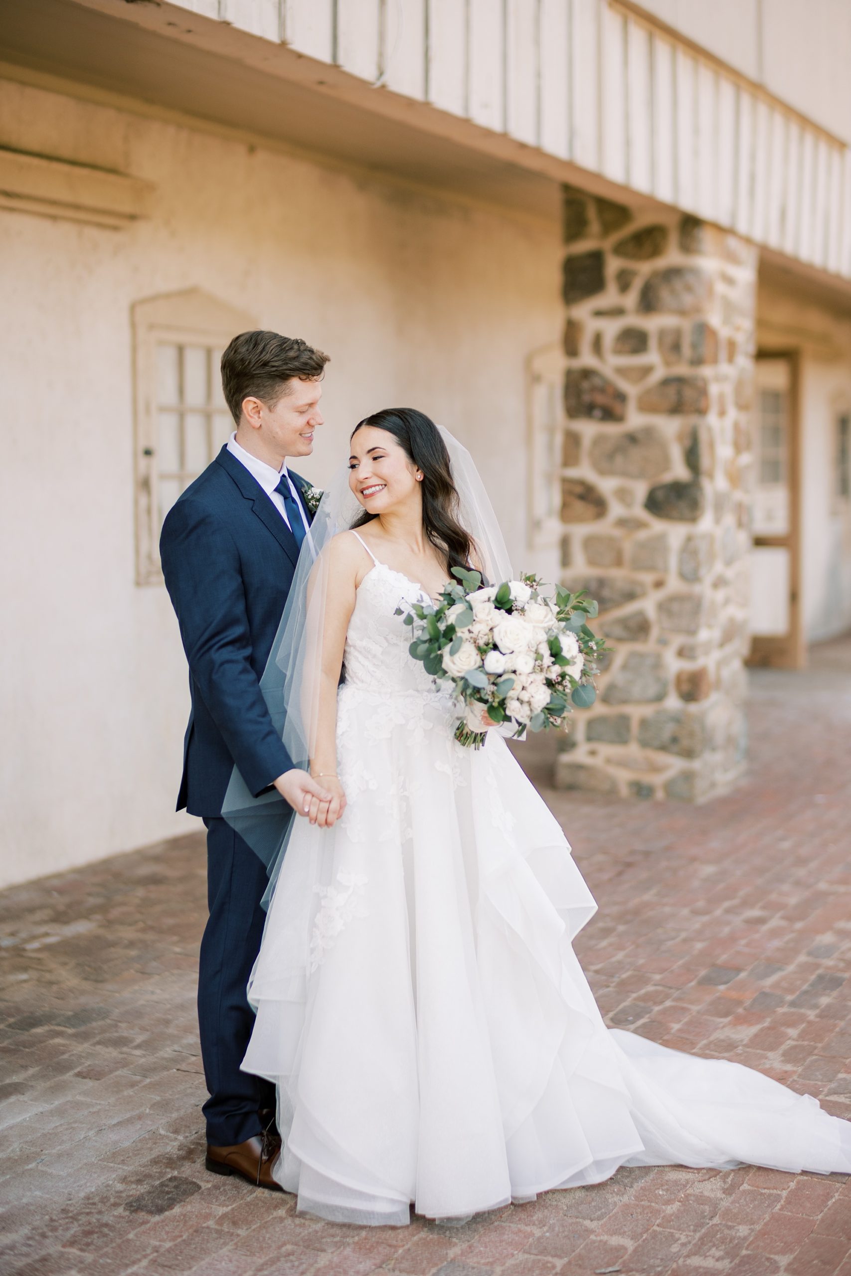 bride and groom hold hands by stone wall at French Creek Golf Club