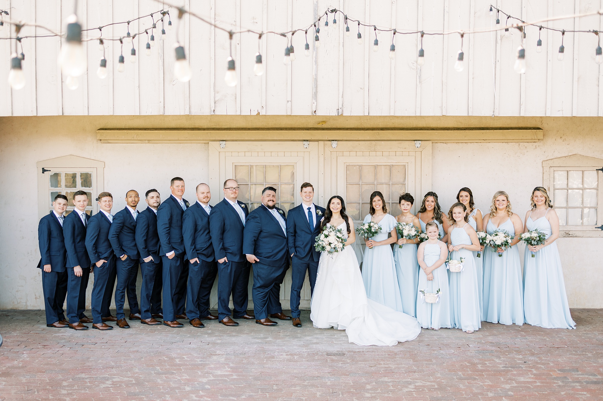 bride and from stands with wedding party in blue attire 