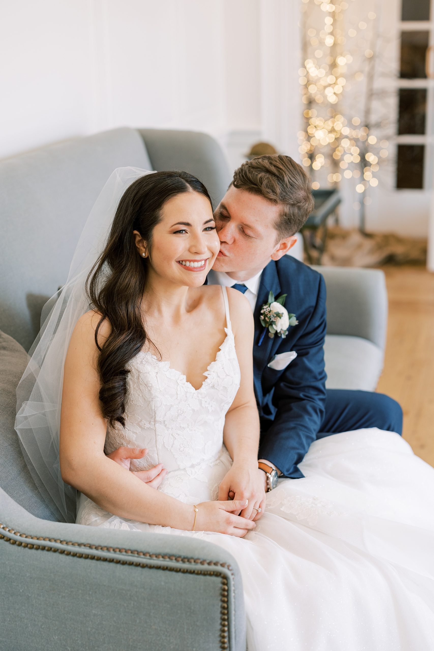 groom kisses bride's cheek sitting on couch at French Creek Golf Club