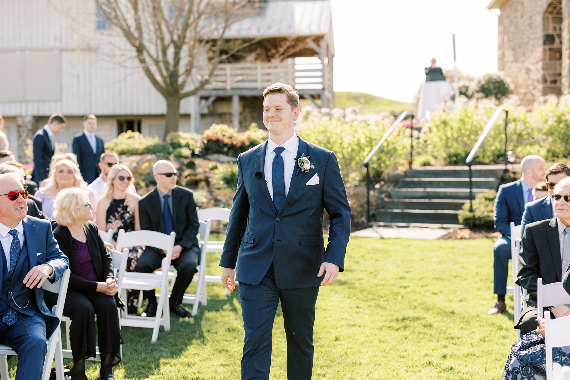 groom walks down aisle during outdoor wedding ceremony on the lawn of French Creek Golf Club