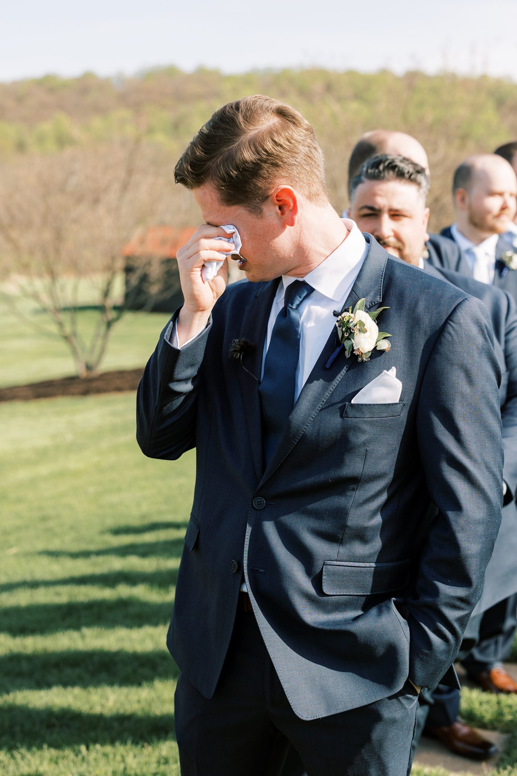 groom wipes away tears during outdoor wedding ceremony on the lawn of French Creek Golf Club