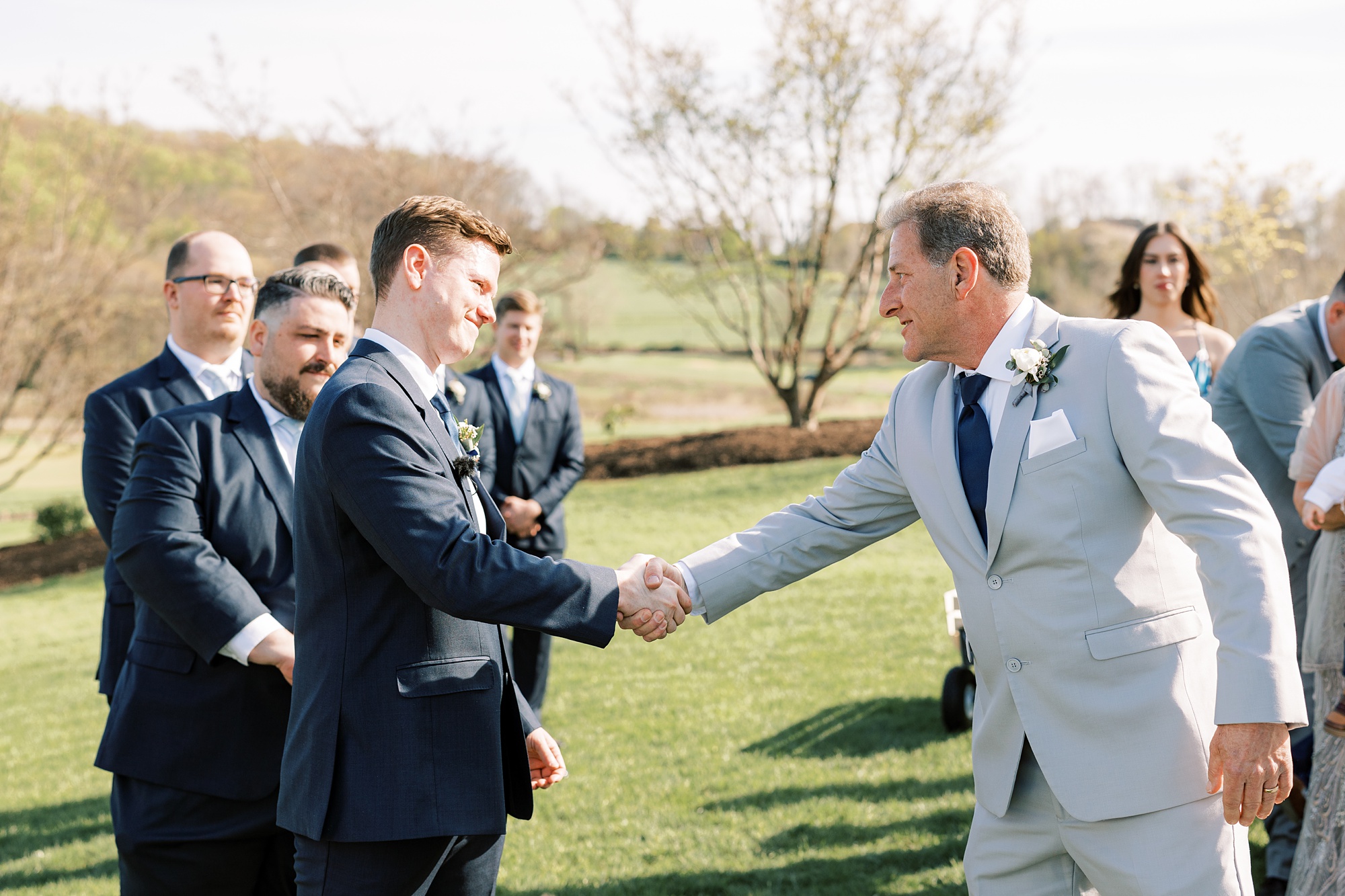 groom shakes father-in-law's hand during outdoor wedding ceremony on the lawn of French Creek Golf Club