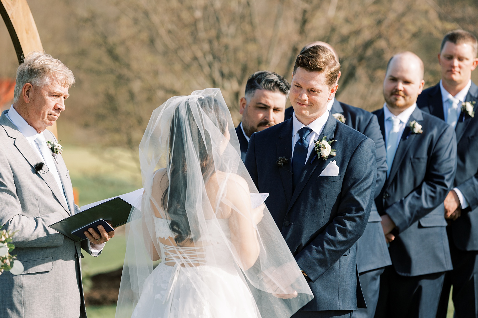 groom smiles at bride during outdoor wedding ceremony on the lawn of French Creek Golf Club