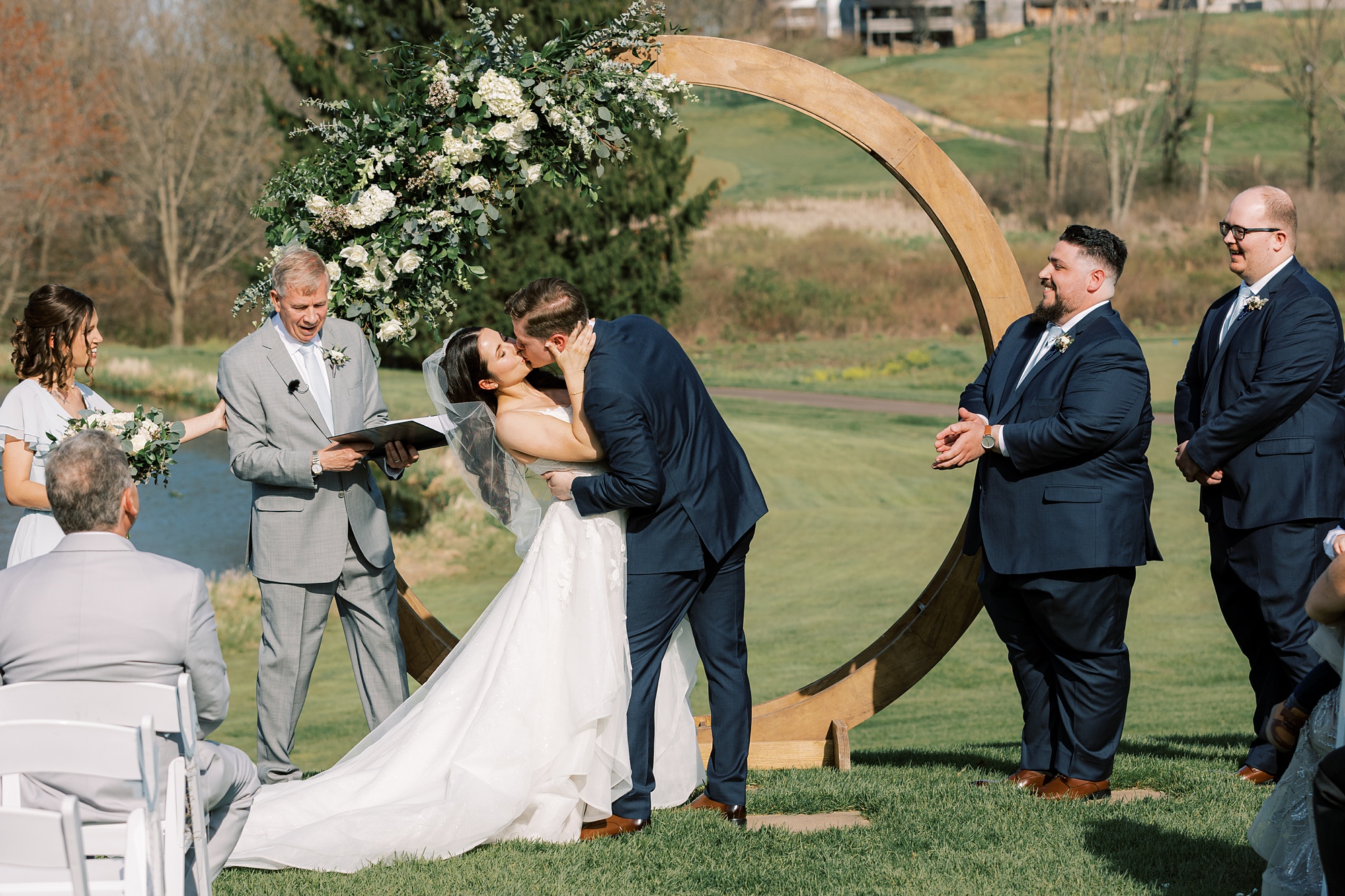 newlyweds kiss during outdoor wedding ceremony on the lawn of French Creek Golf Club
