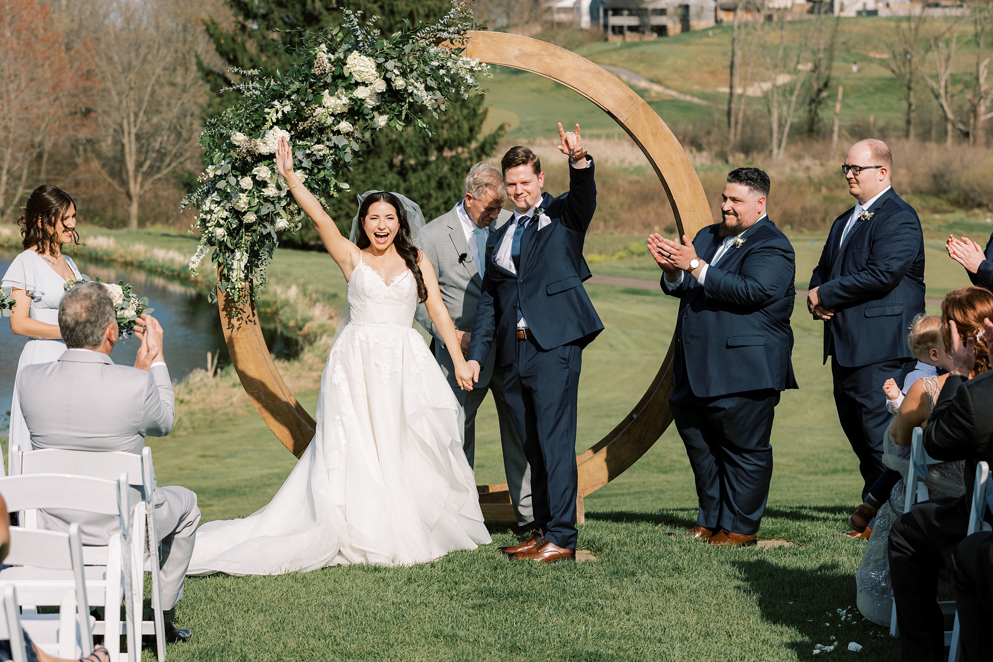 bride and groom cheer by wooden circular arbor 