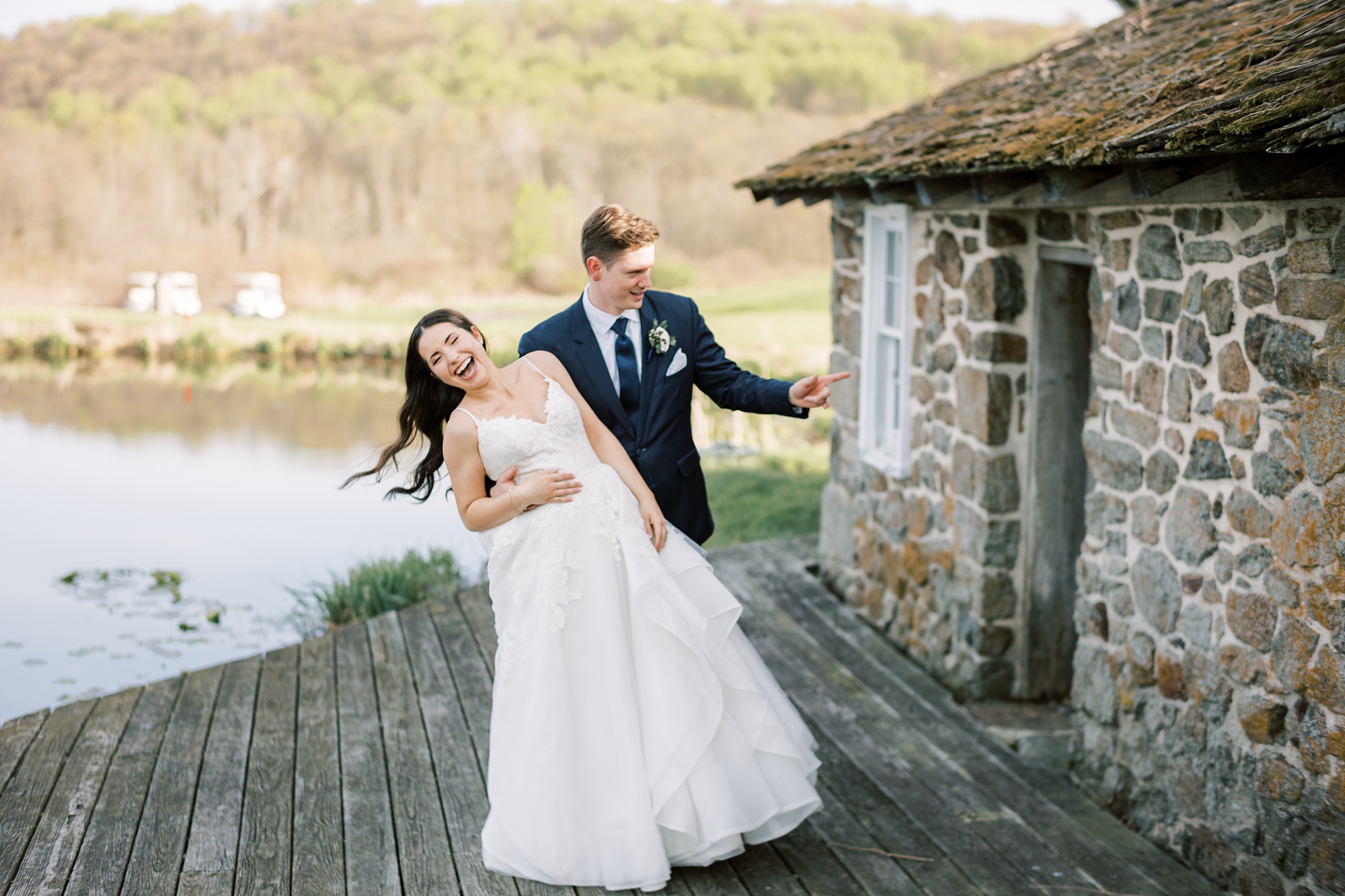 groom dips bride during portraits near stone house 
