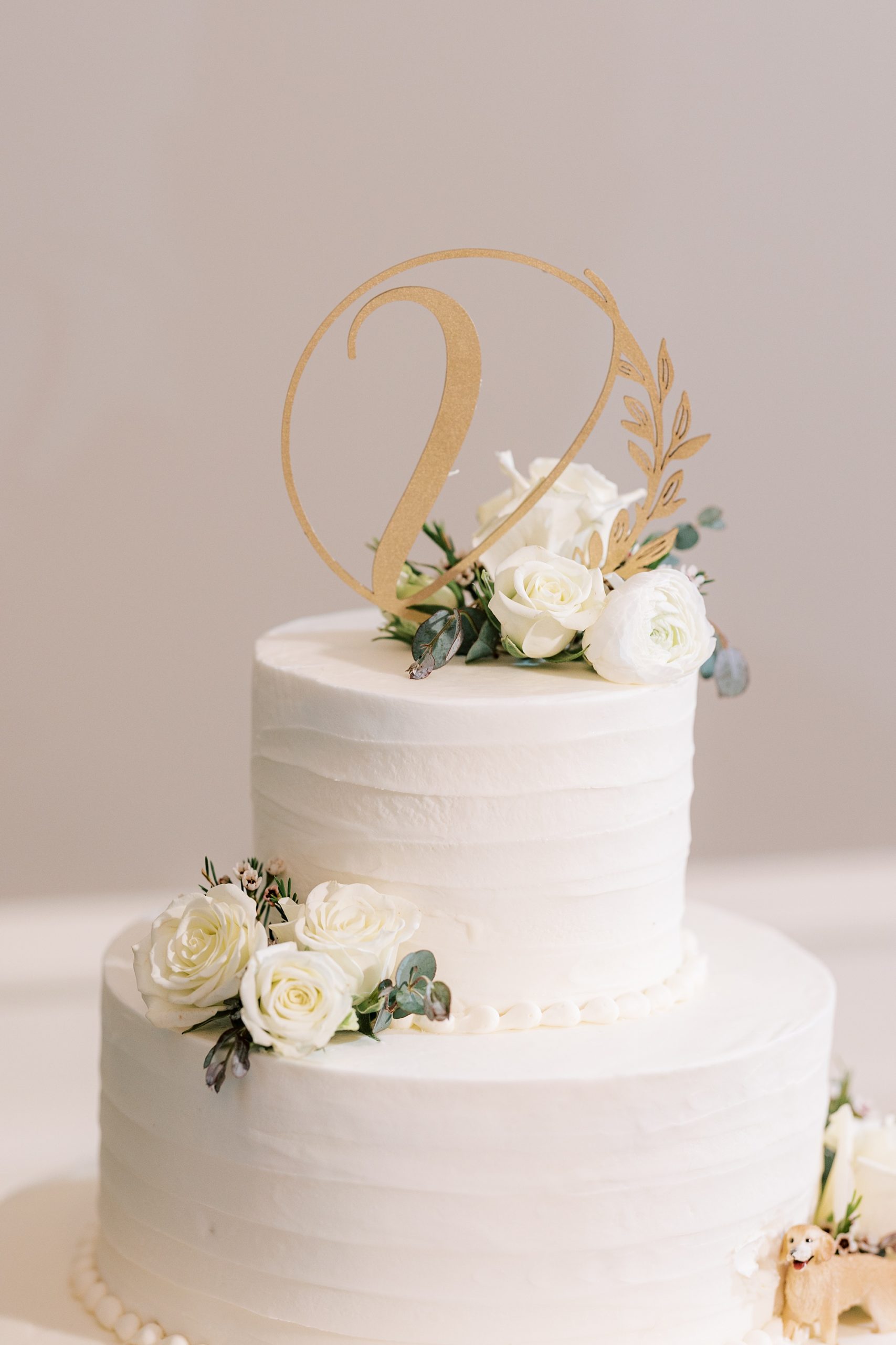 wedding cake with white flowers and gold cake topper 