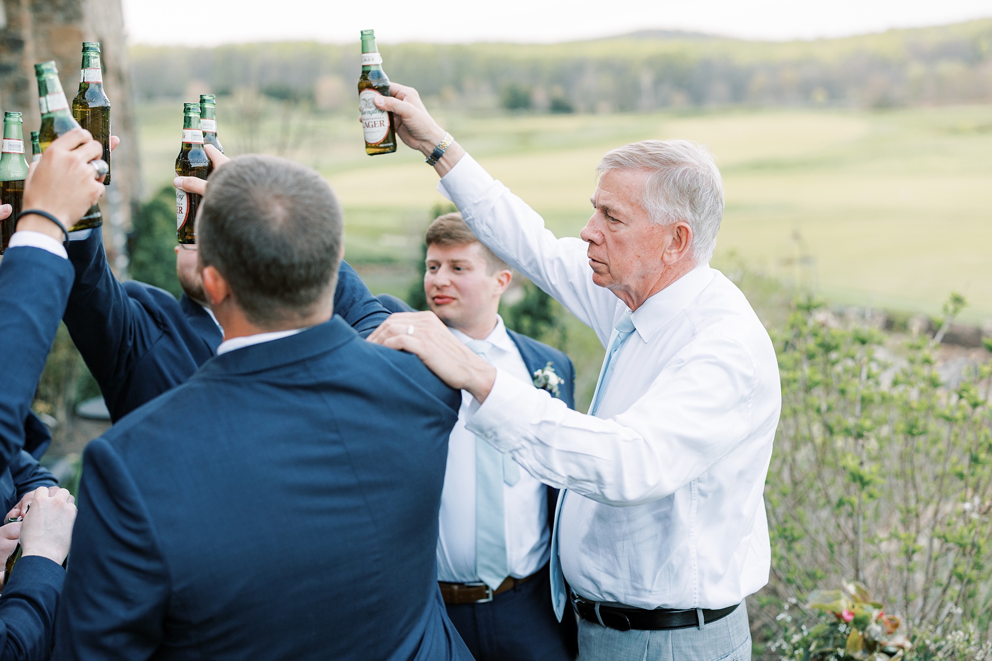 groomsmen and dad lift beer in toast during Chester County PA wedding reception