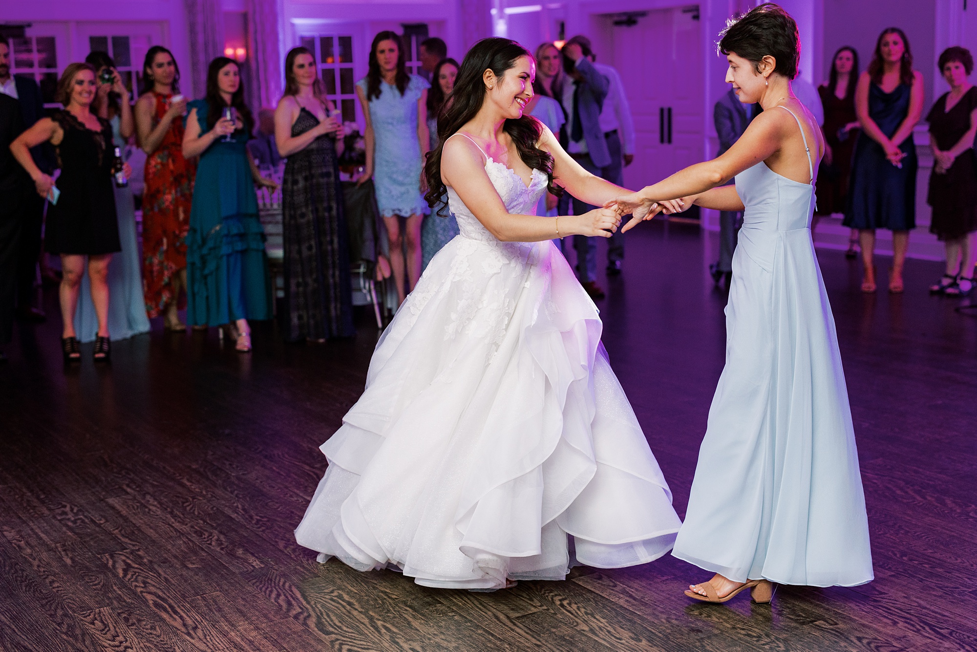 bride dances with bridesmaid in blue dress