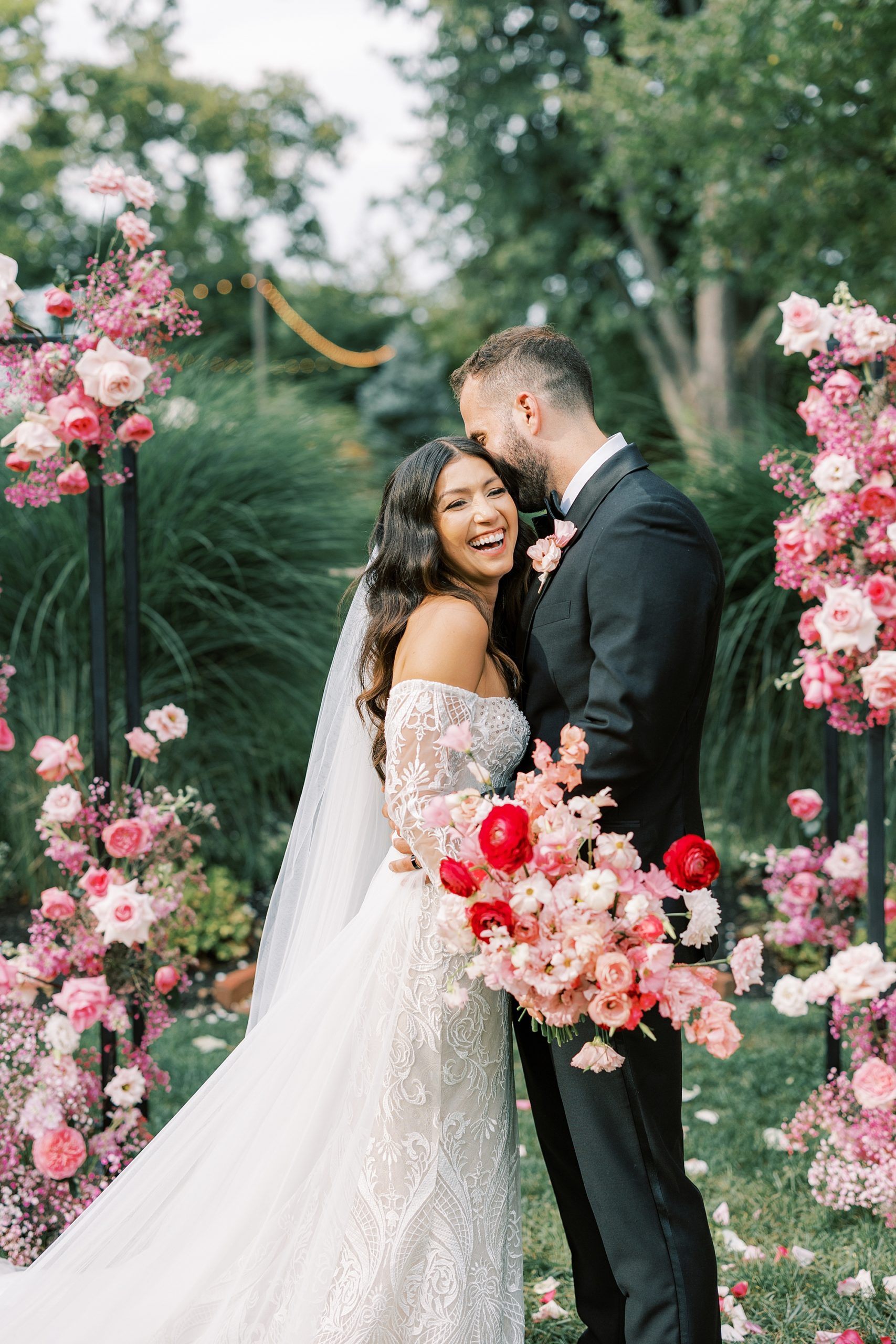 groom makes bride laugh in front of pink monochromatic floral display at The Cypress House