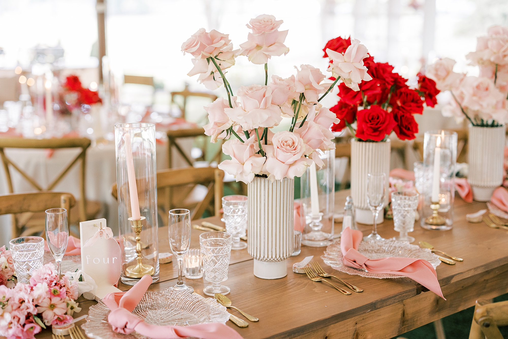 pink floral centerpieces in white vases under tent at The Cypress House