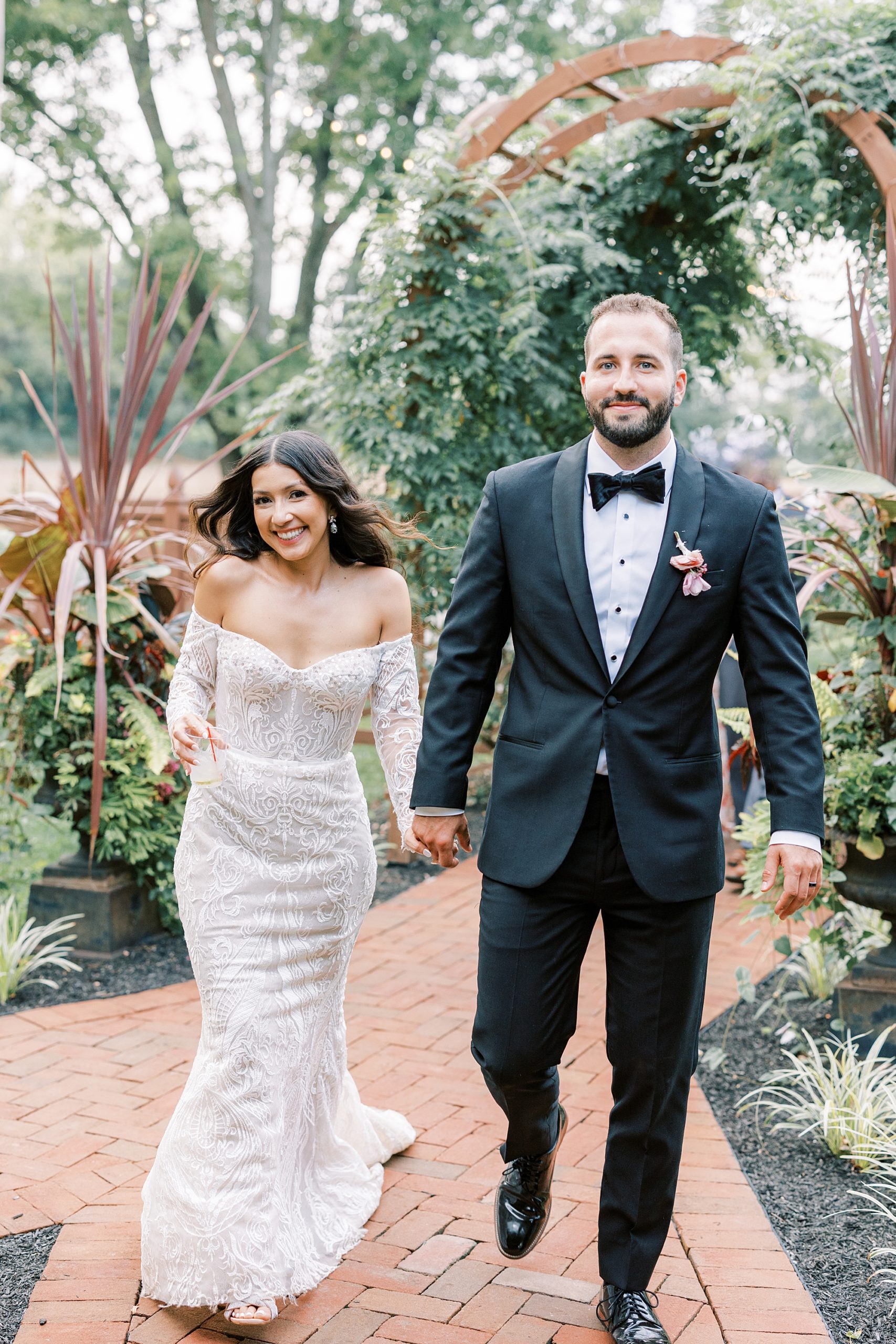 newlyweds smile walking through gardens at The Cypress House