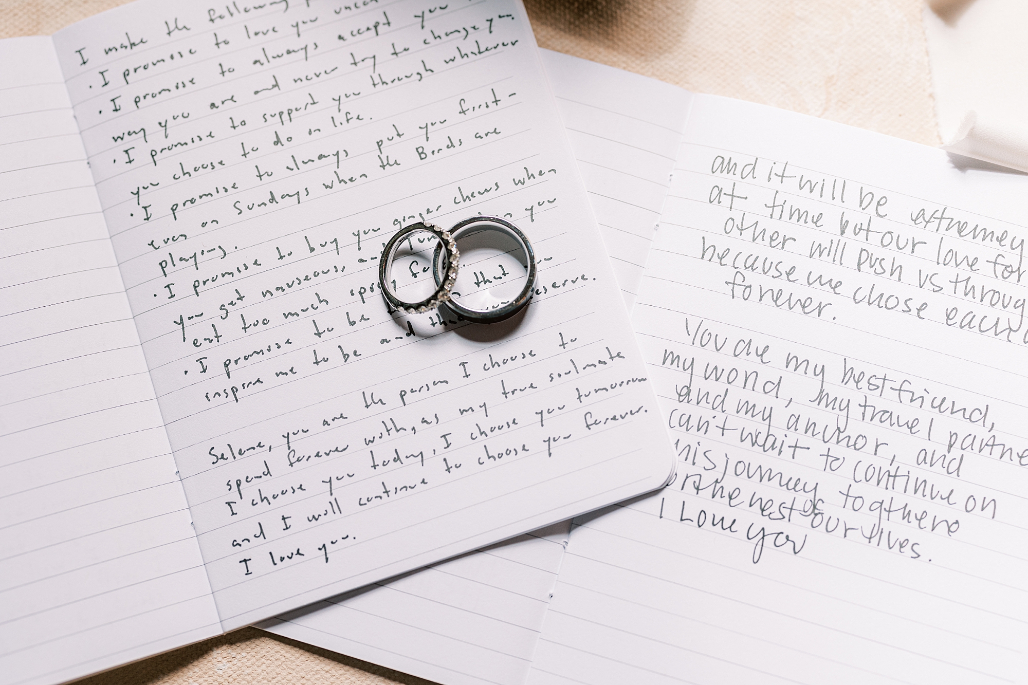 wedding rings rest on handwritten vow booklets