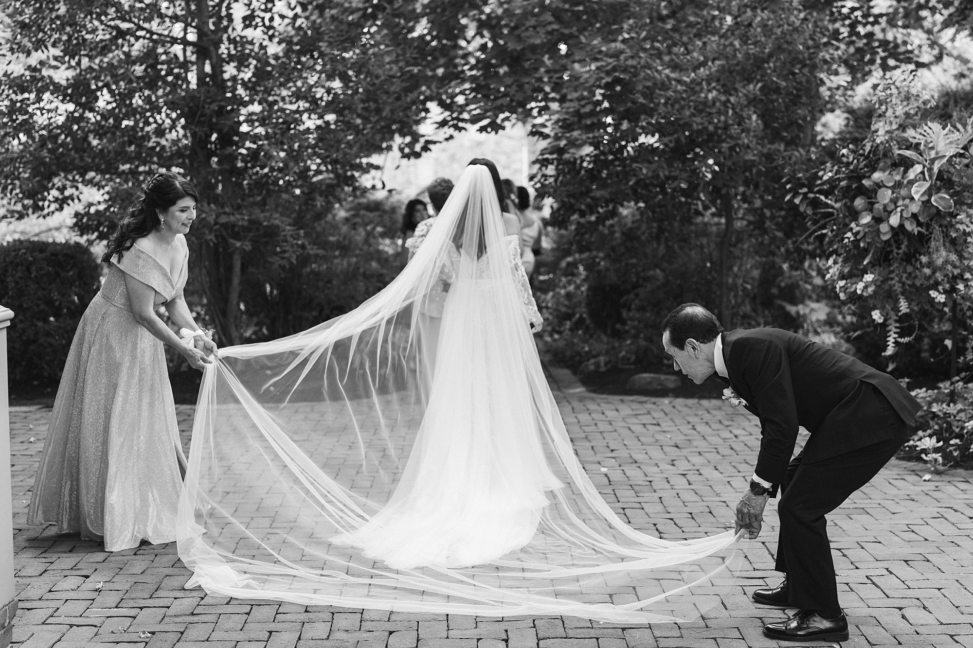 father and mother help bride adjust veil before ceremony 