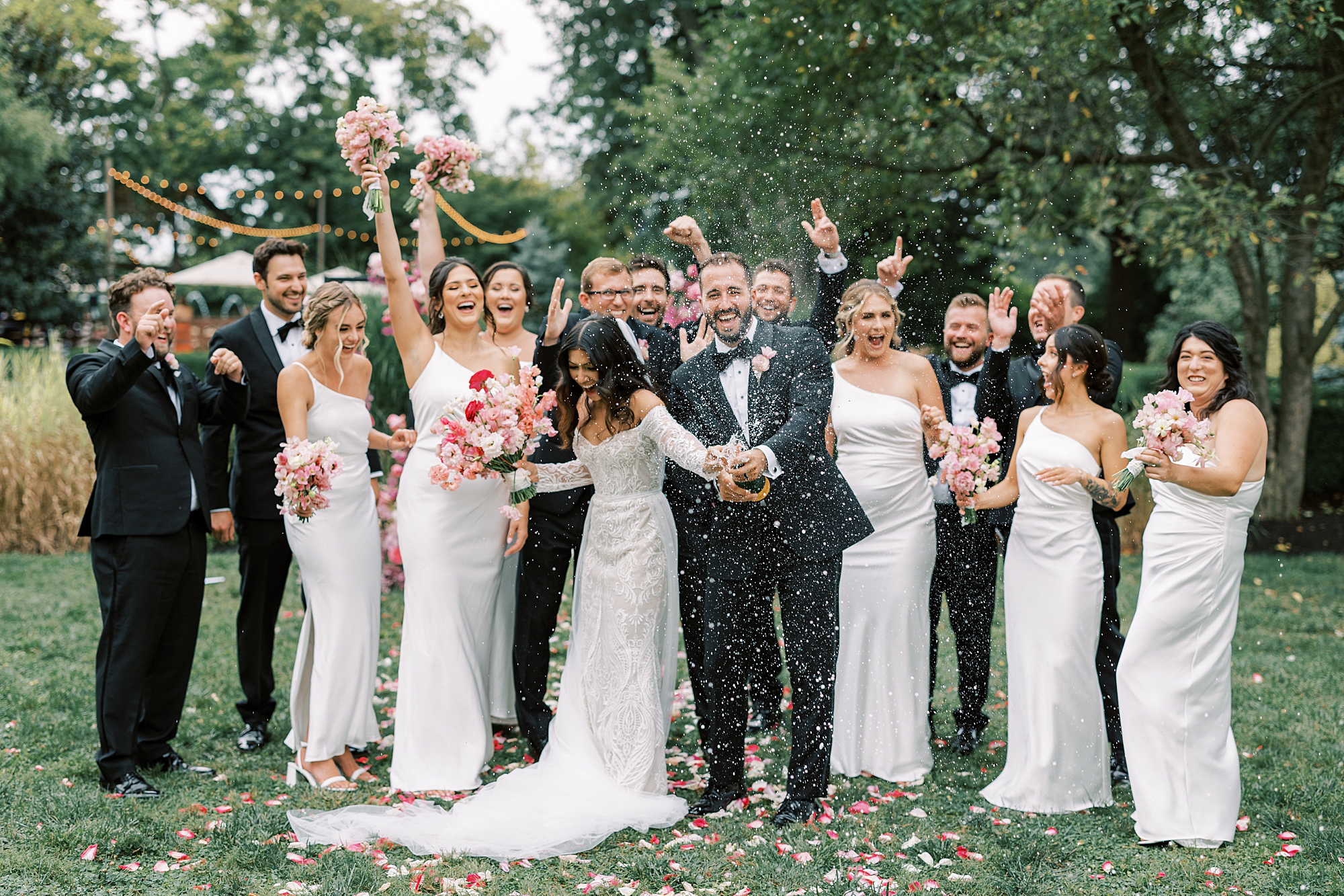 bride and groom laugh popping Champagne with wedding party at The Cypress House