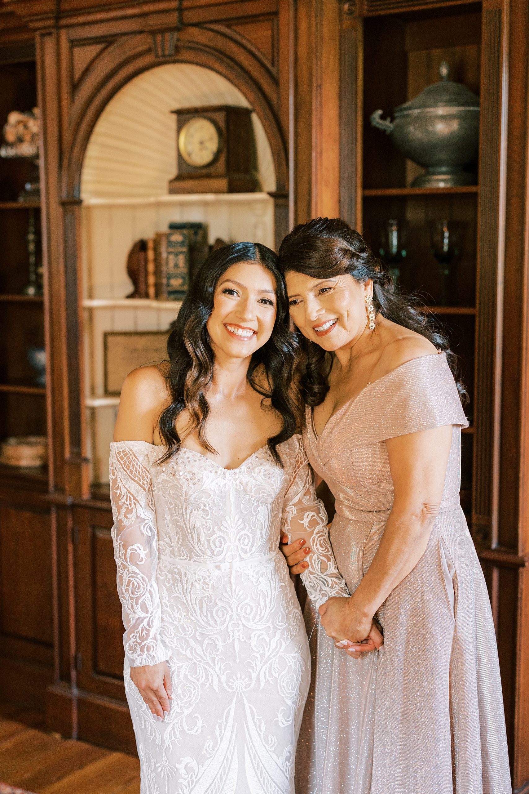 mother in pink gown leans head into bride during prep at The Cypress House