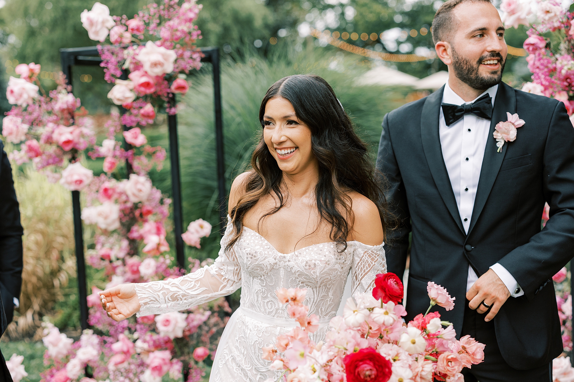 bride smiles in front of pink floral display at ceremony 