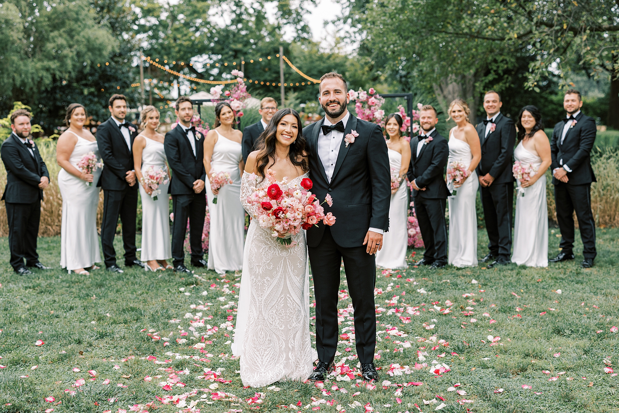 bride and groom stand together in front of wedding party in black and white 