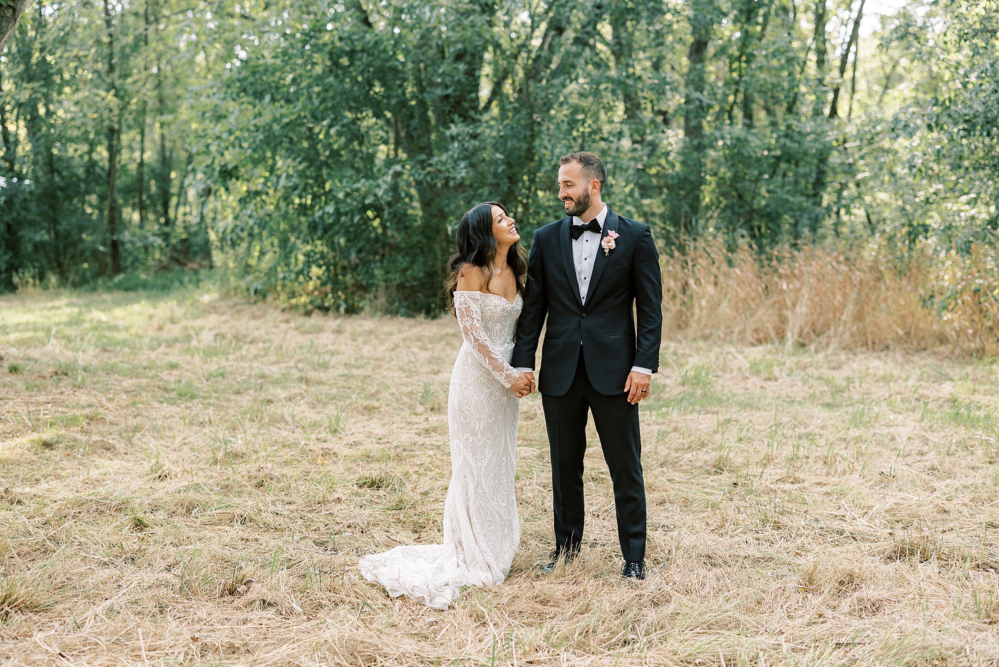  newlyweds stand holding hands in field at The Cypress House