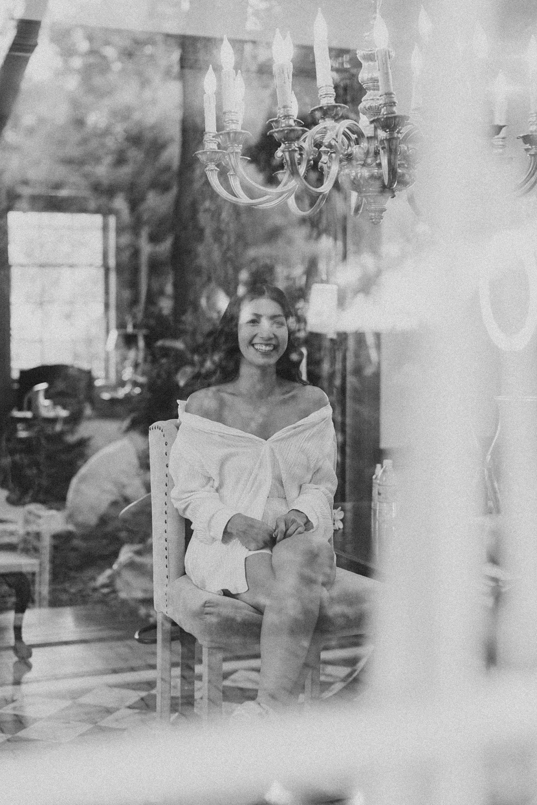 bride smiles in mirror in robe preparing for wedding day 