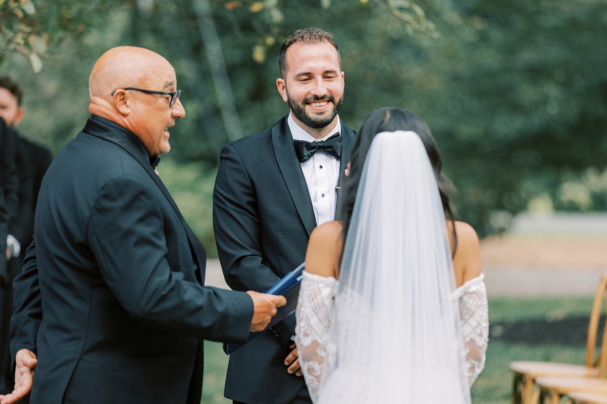 groom holds hands with bride during ceremony at The Cypress House