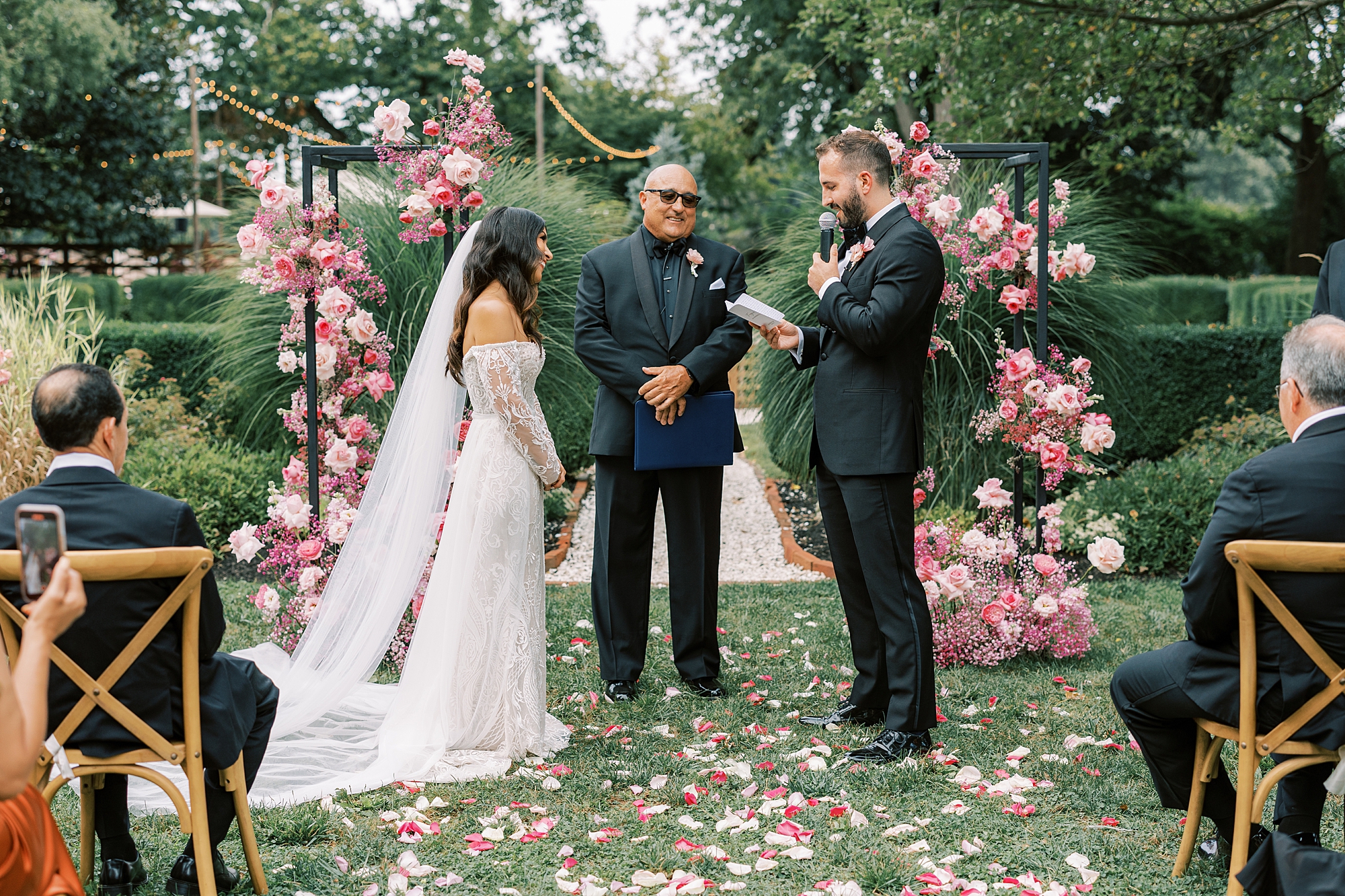 groom reads vows from book during ceremony on the lawn at The Cypress House