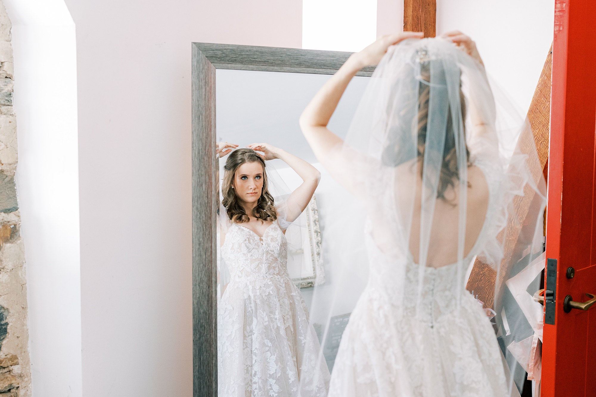 bride adjusts veil in mirror before Tyler Arboretum wedding