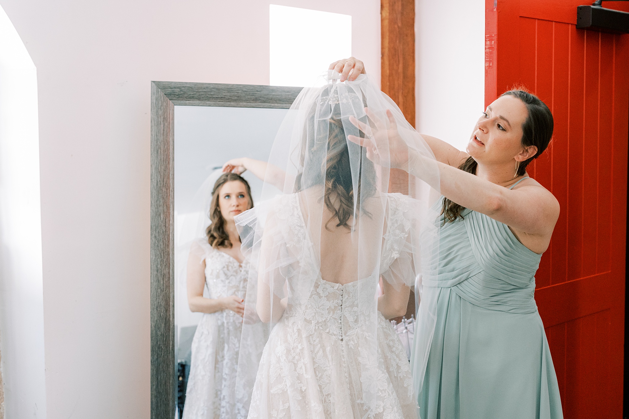 bridesmaid helps bride with veil before PA wedding day