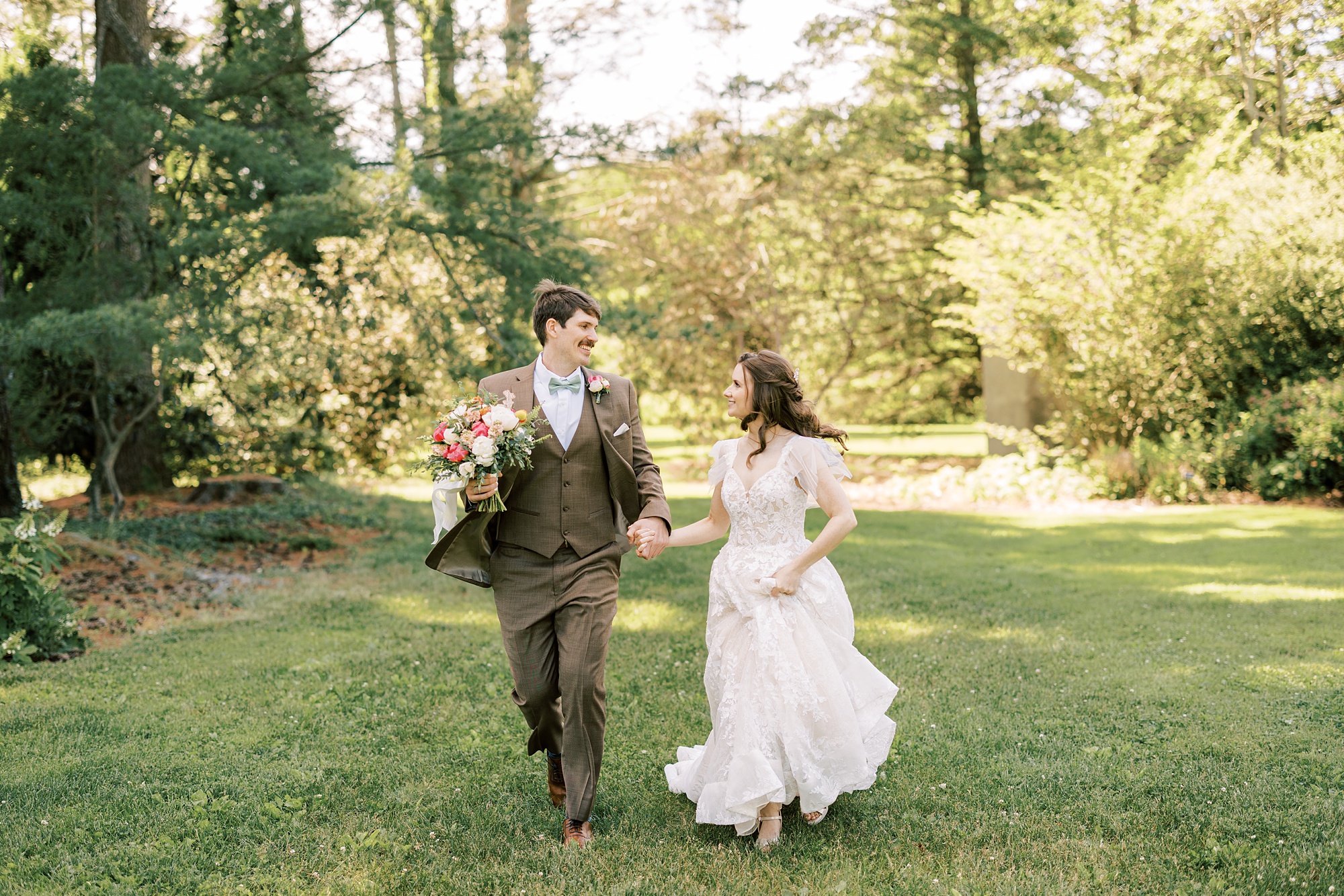 bride and from hold hands running through Tyler Arboretum