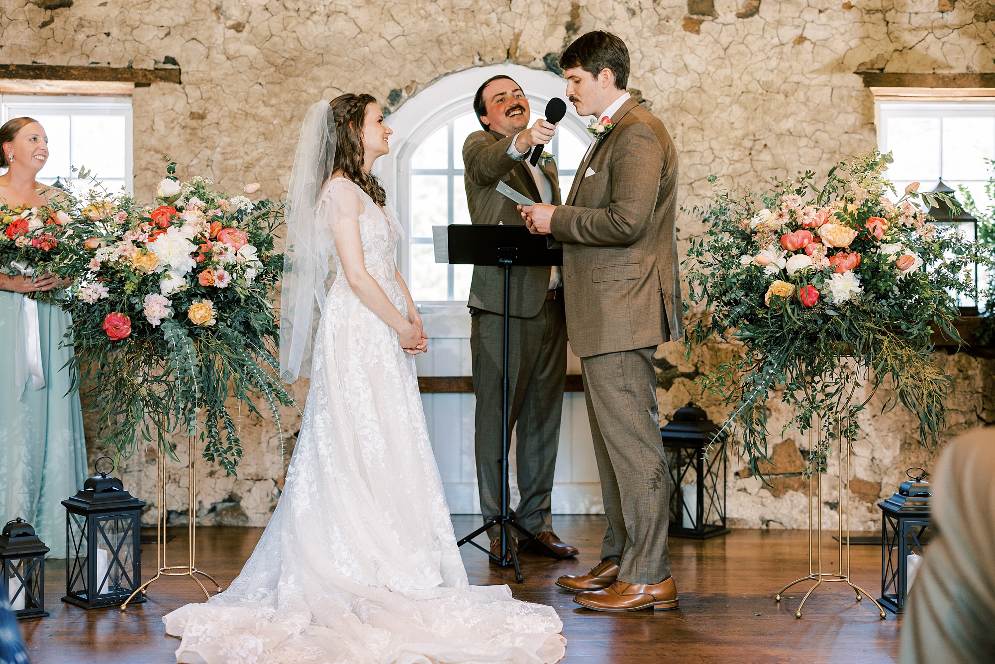 groom reads vows to bride during wedding ceremony inside the stone barn at Tyler Arboretum