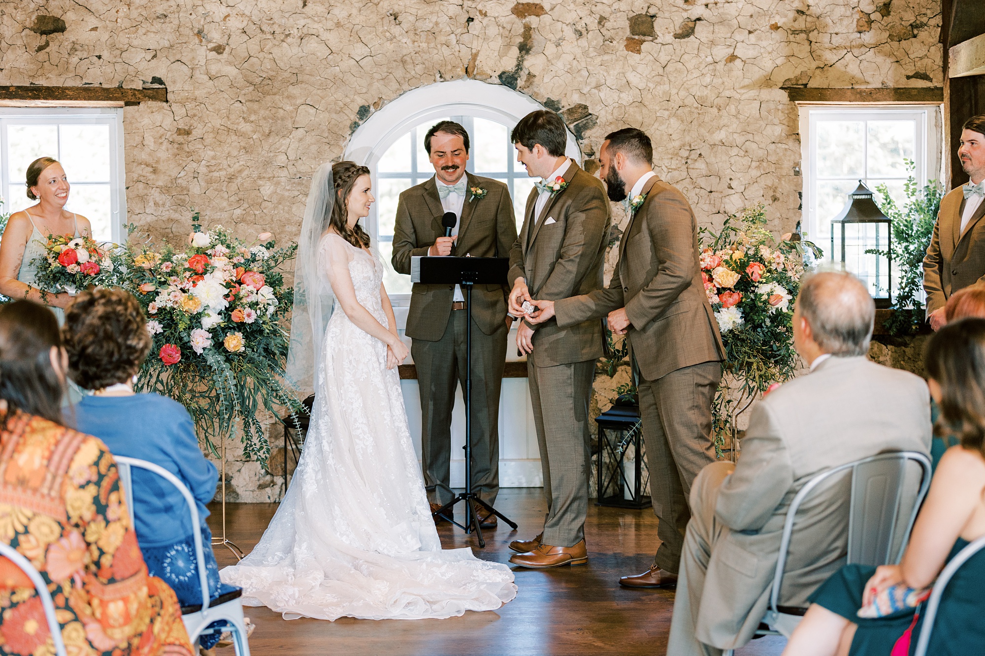 couple exchanges vows during wedding ceremony inside the stone barn at Tyler Arboretum