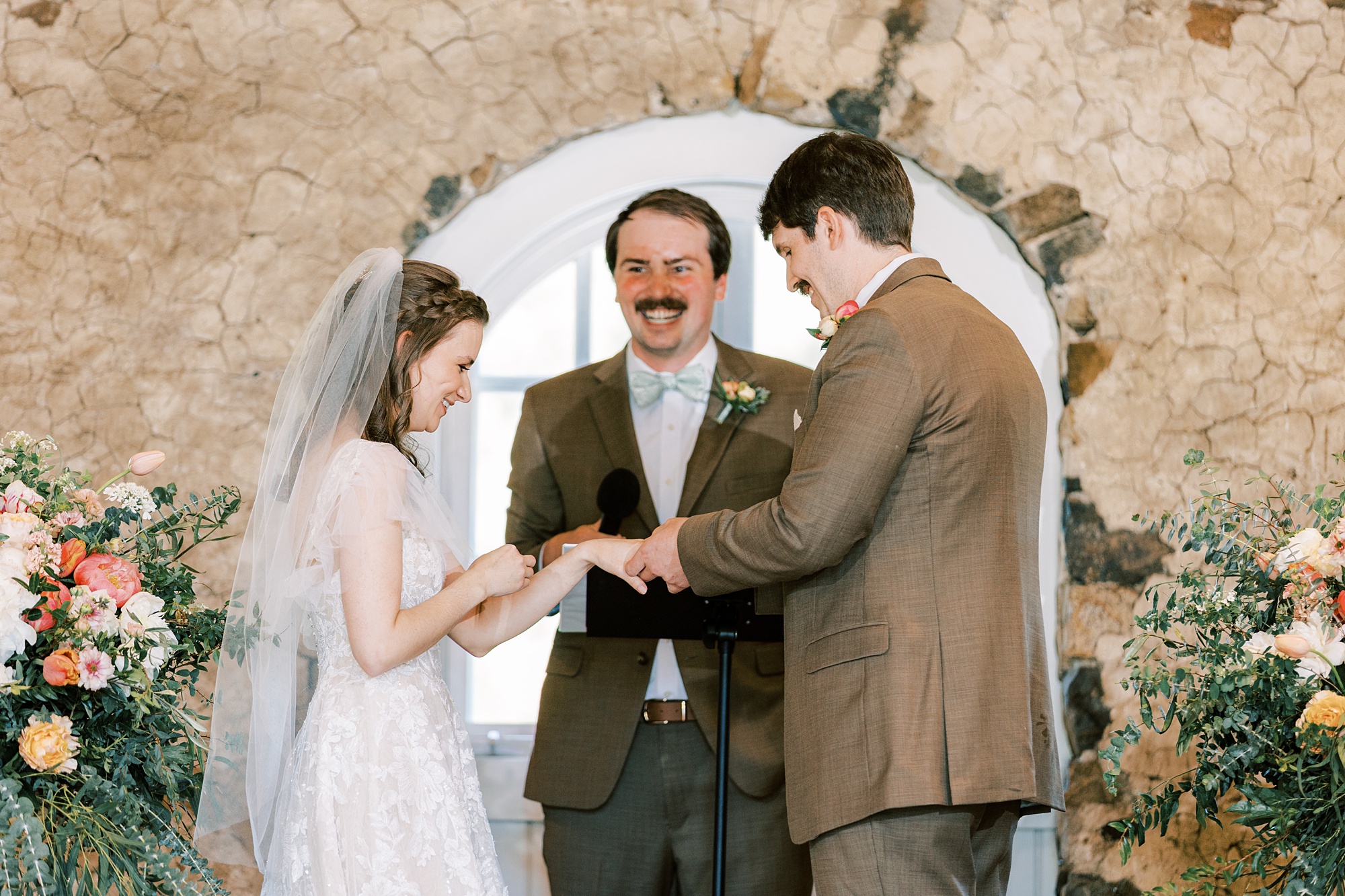 officiant laughs during wedding ceremony inside the stone barn at Tyler Arboretum