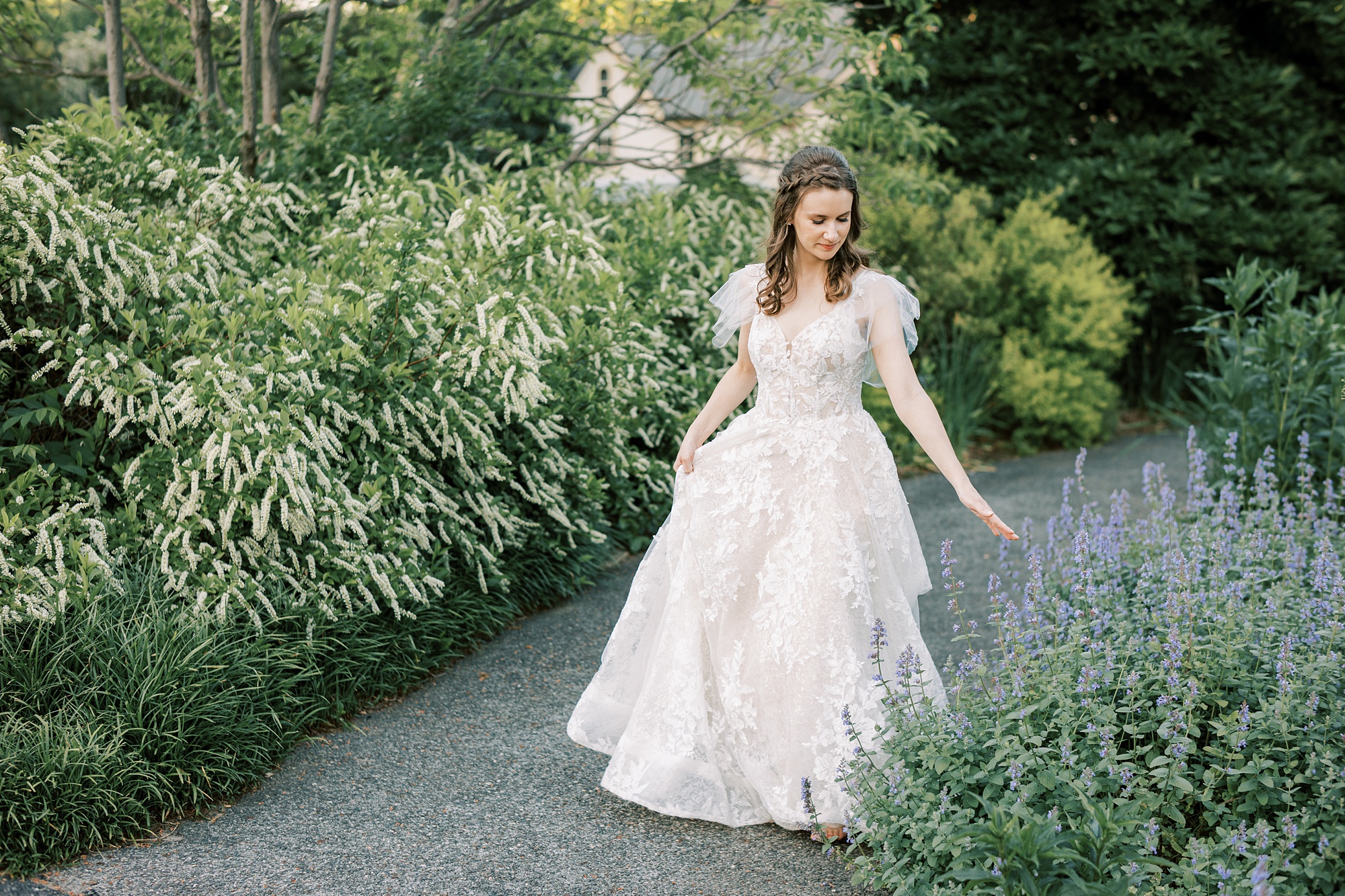 bride walks through garden touching plants with her hands 