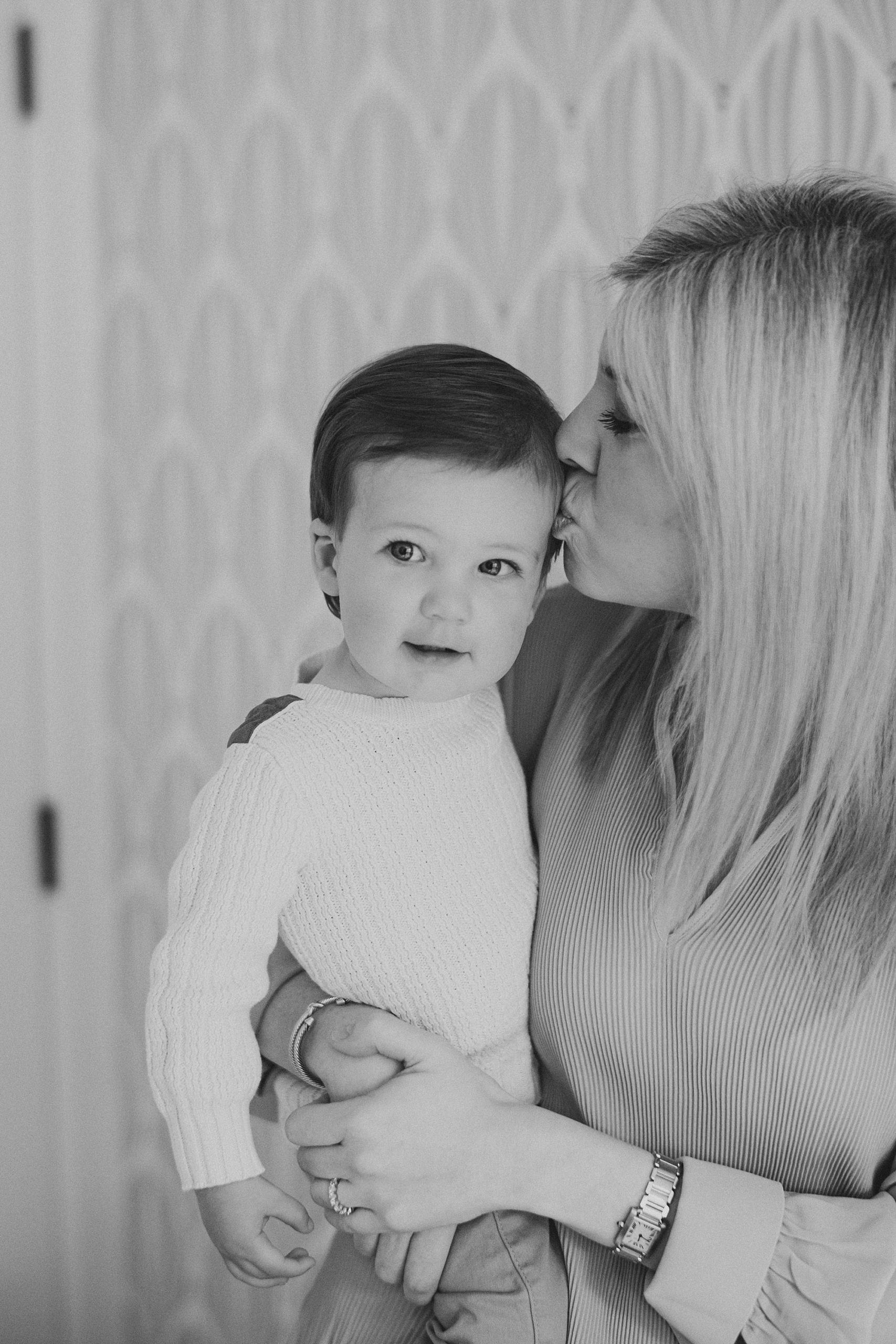 mom kisses toddler brother during family photos at home 